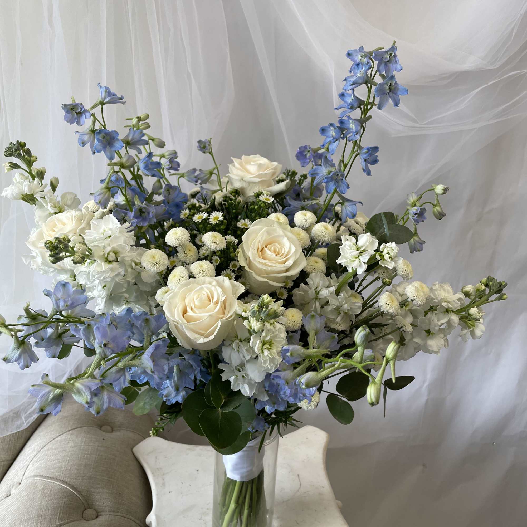 Blue and white bouquet with roses in a clear glass vase
