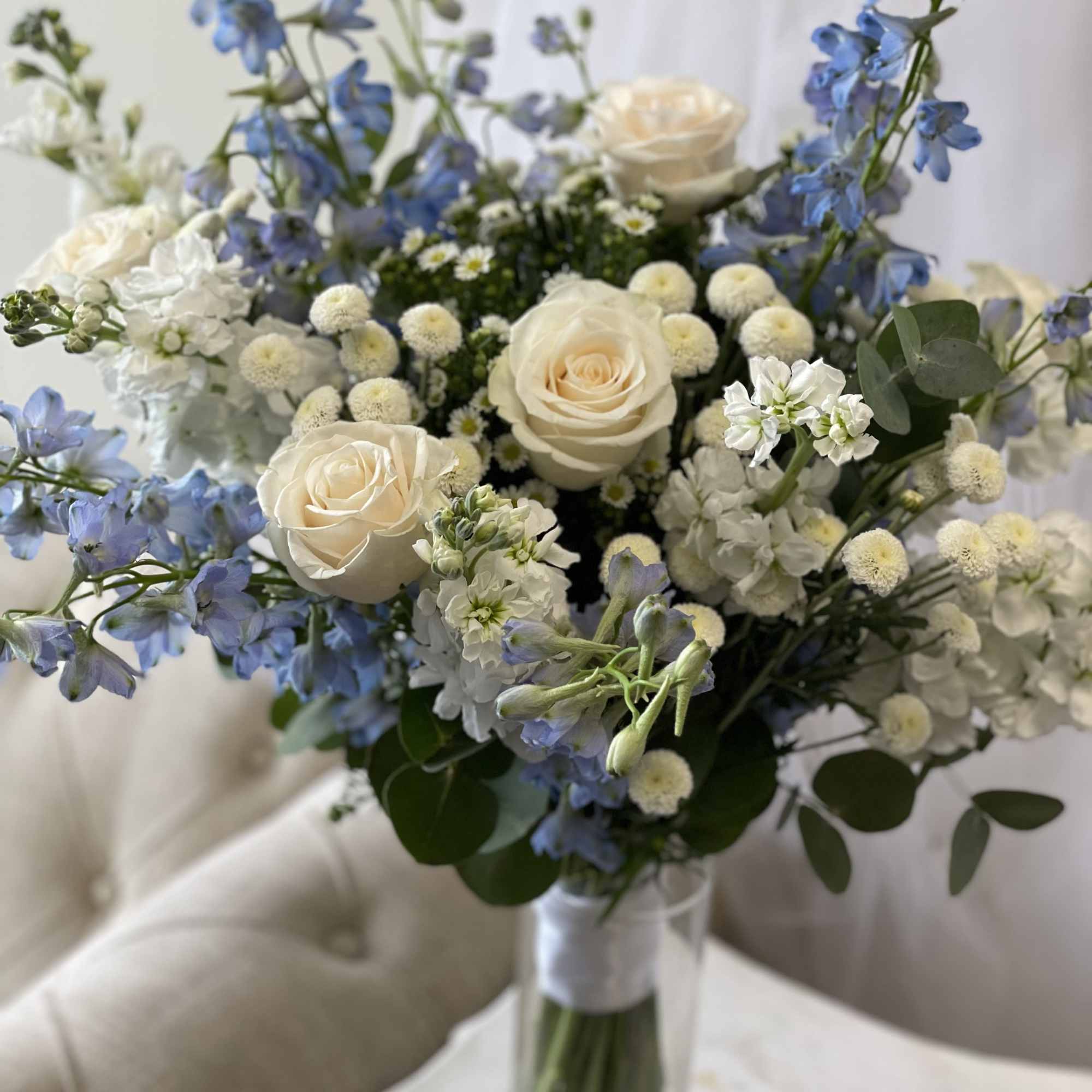 Bouquet of white roses and blue flowers in a glass vase
