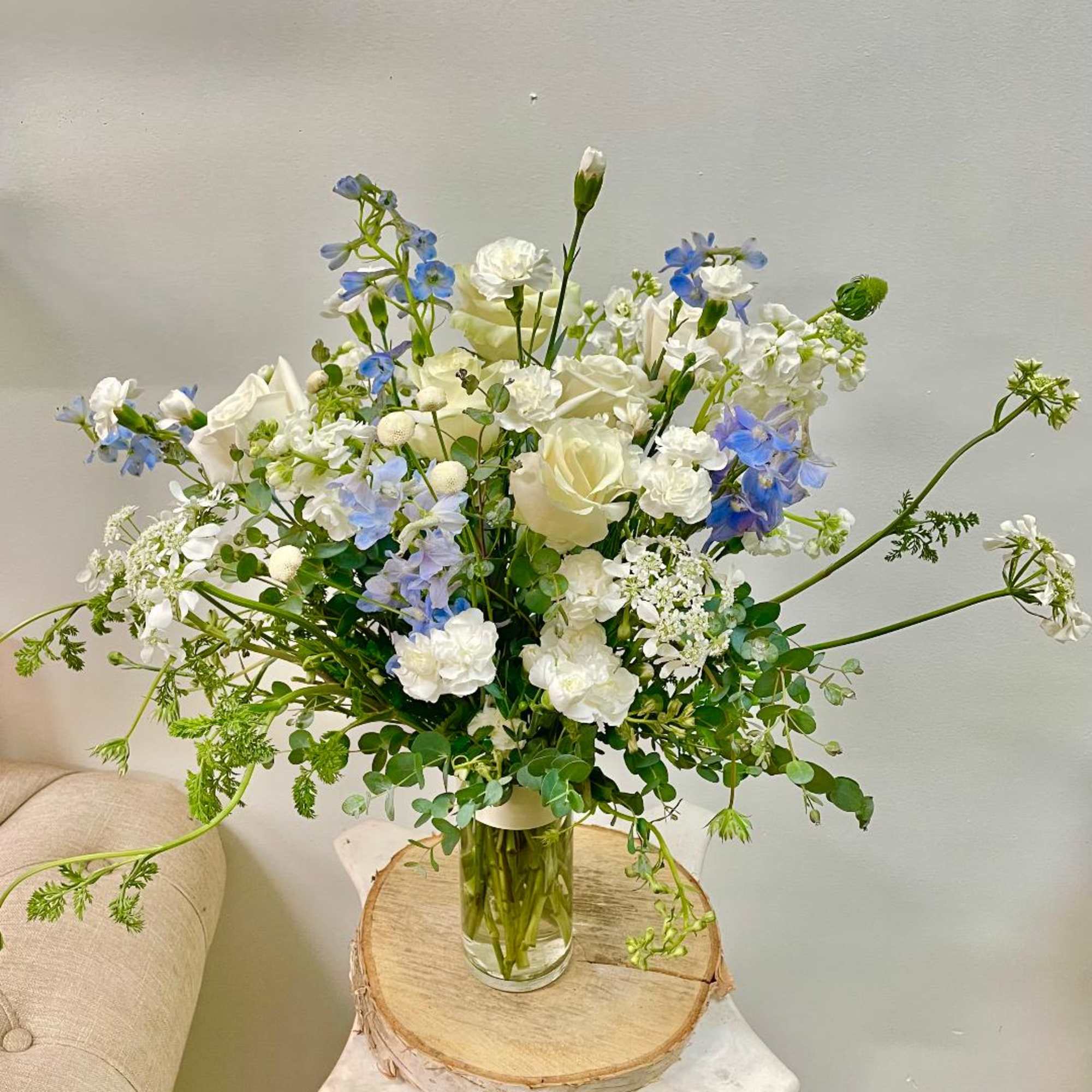 White and blue floral arrangement in a clear glass vase