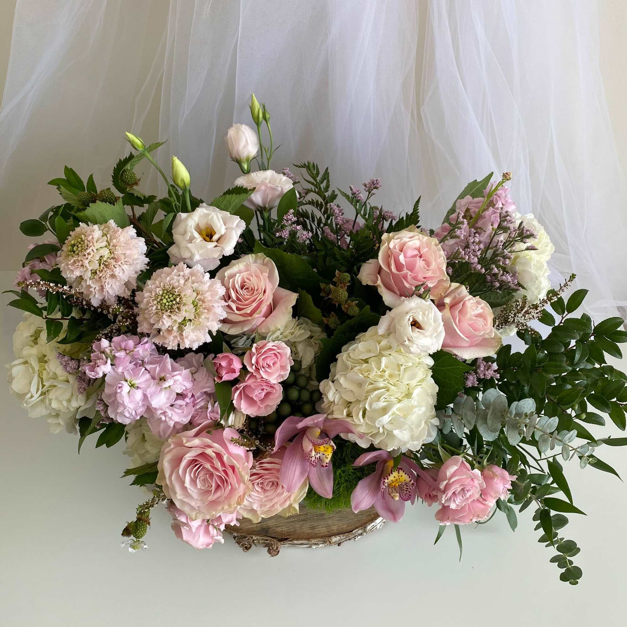 Large pastel floral arrangement in a low wooden container