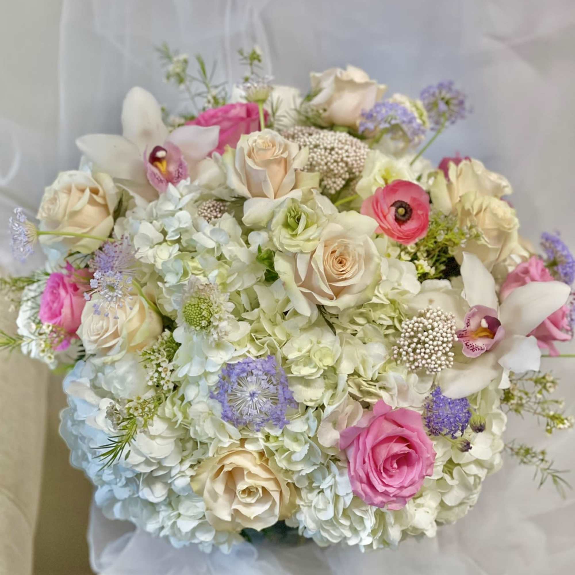 Bouquet of pastel roses, hydrangeas, orchids, and lavender blooms