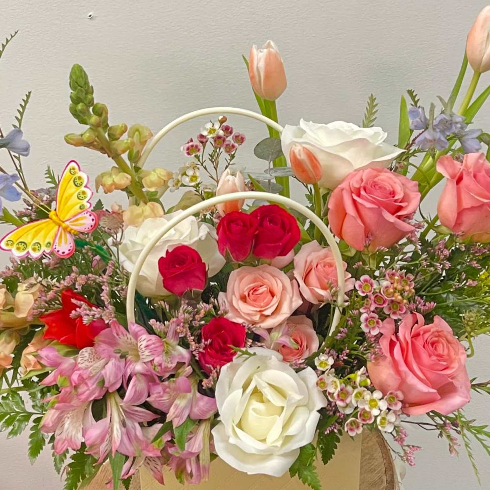 Mixed bouquet of roses, tulips, and alstroemeria in a handled basket
