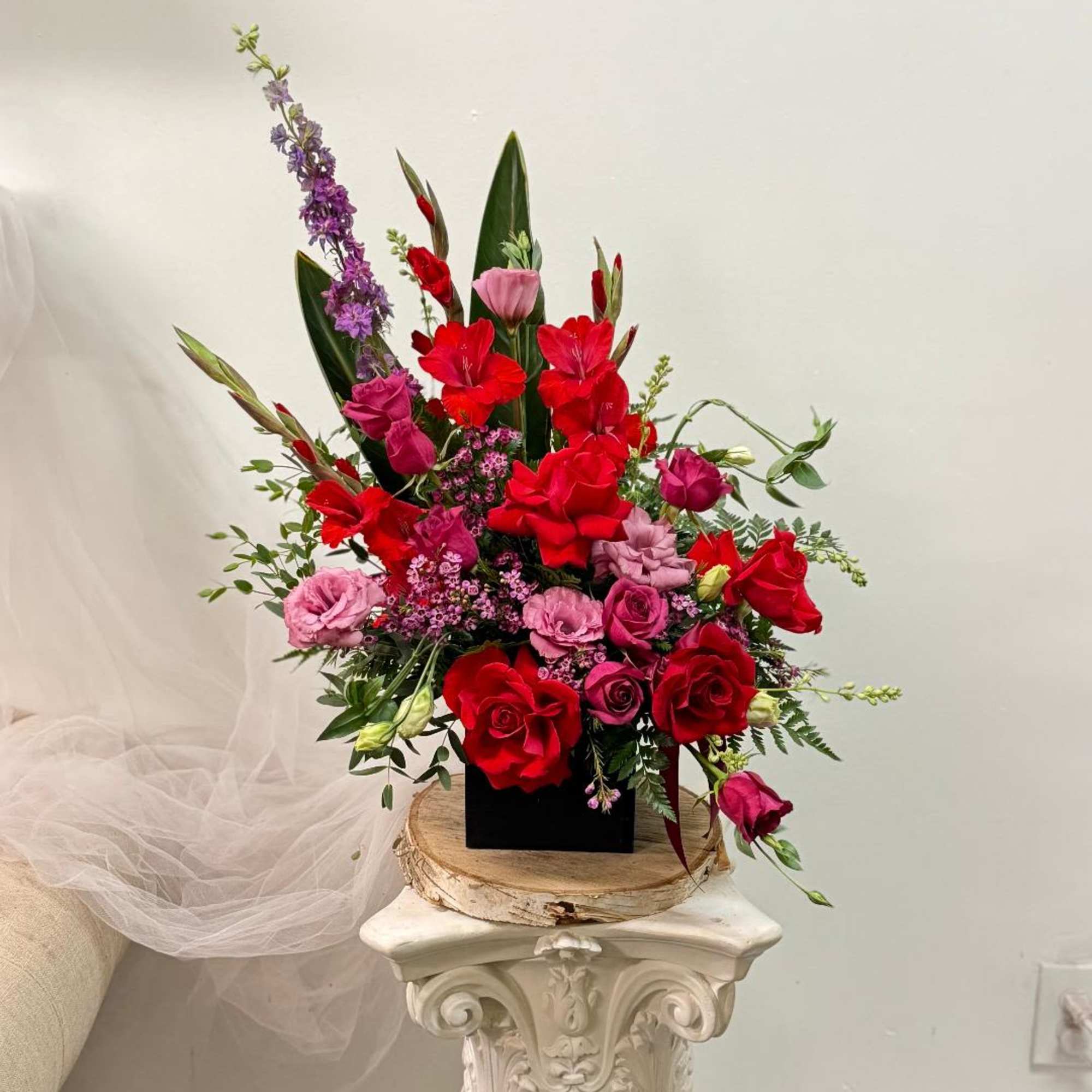 Tall arrangement of red and pink flowers in a black container