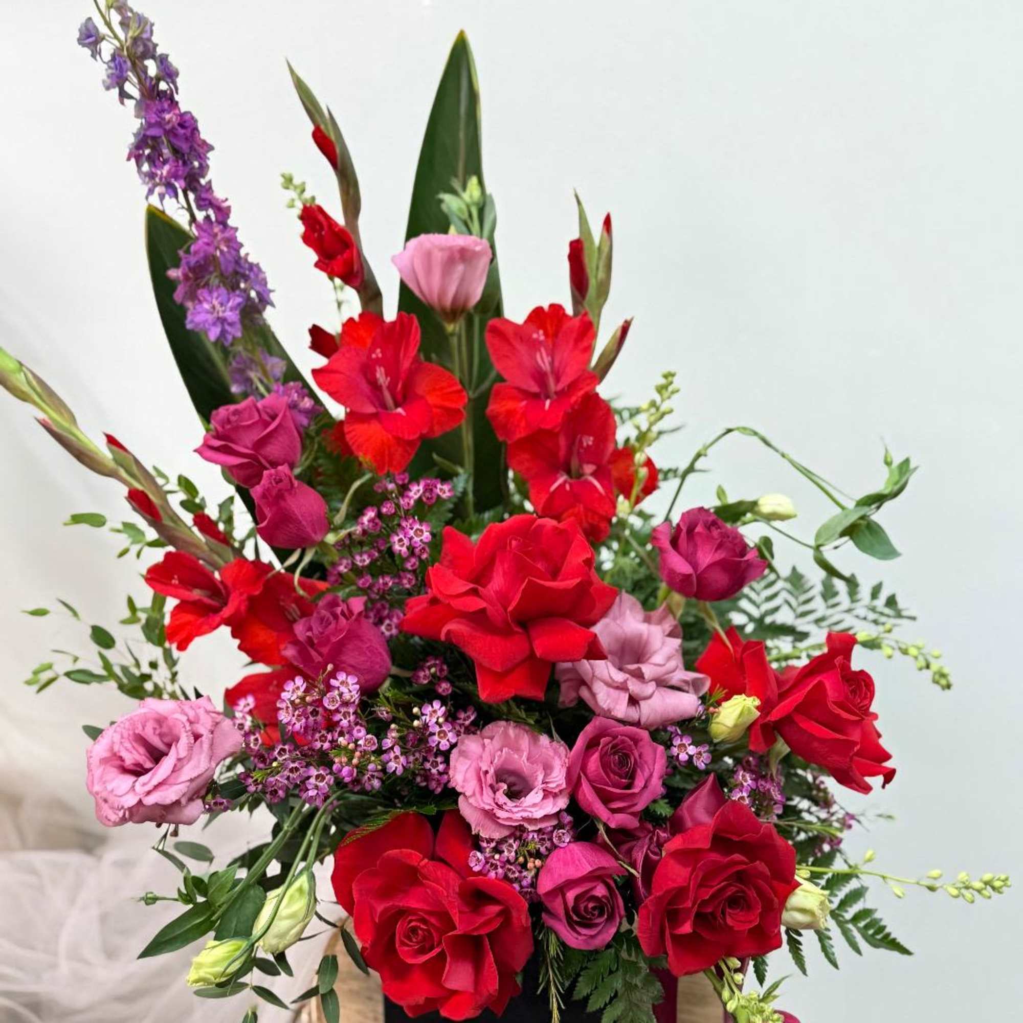 Tall bouquet of red and pink flowers in a black container