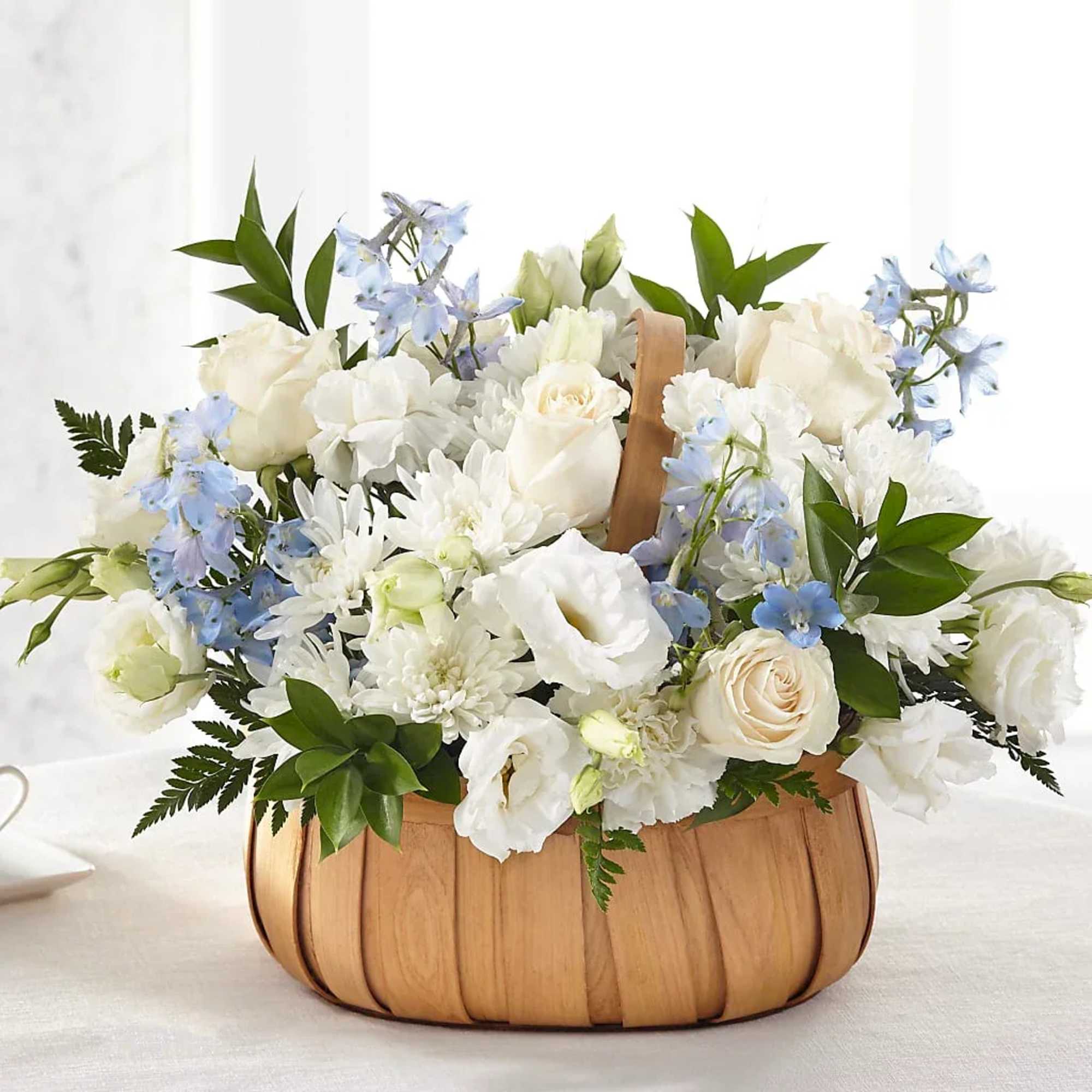 White and pale blue flowers arranged in a wooden basket.