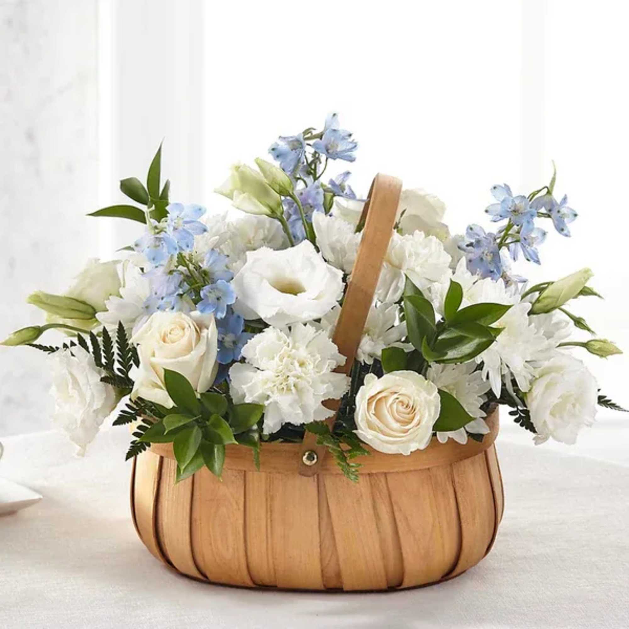 White and blue floral arrangement in a wooden basket