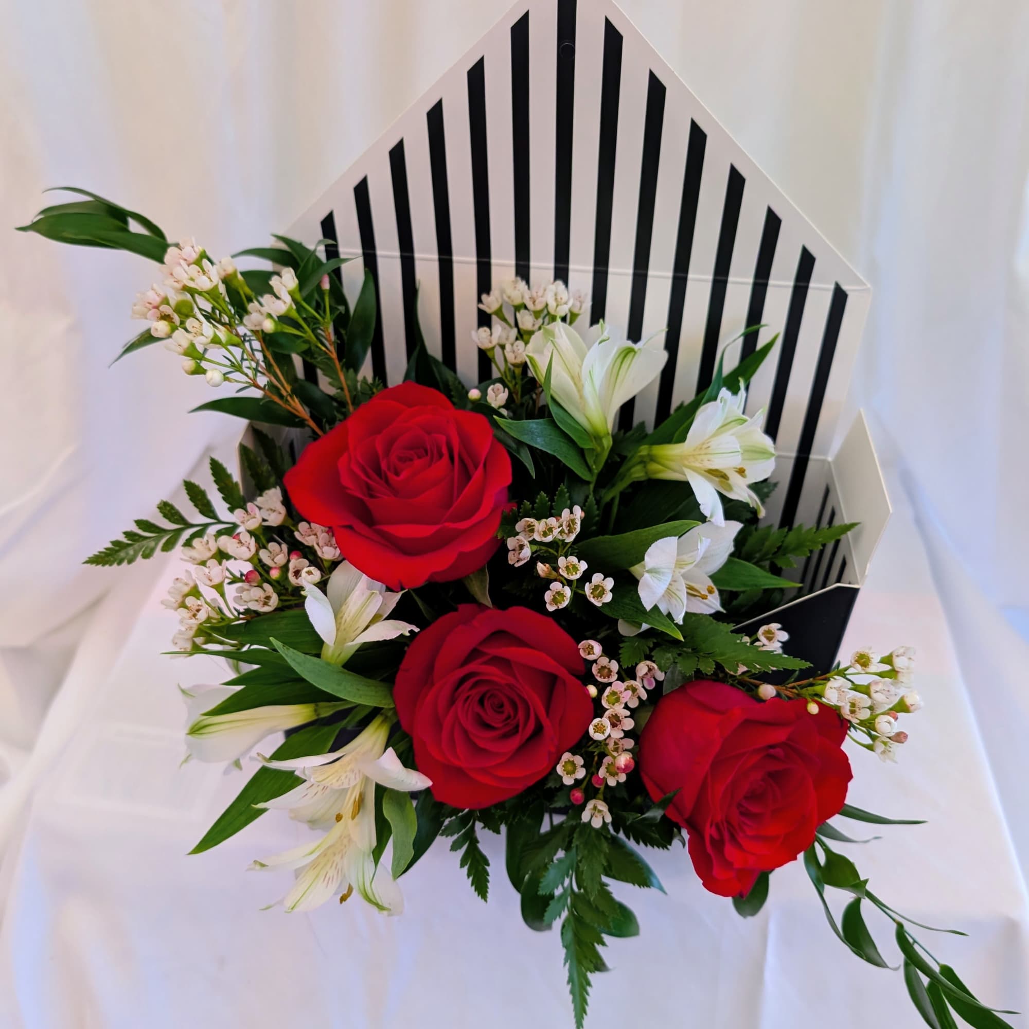 Red roses and white lilies in a striped gift box