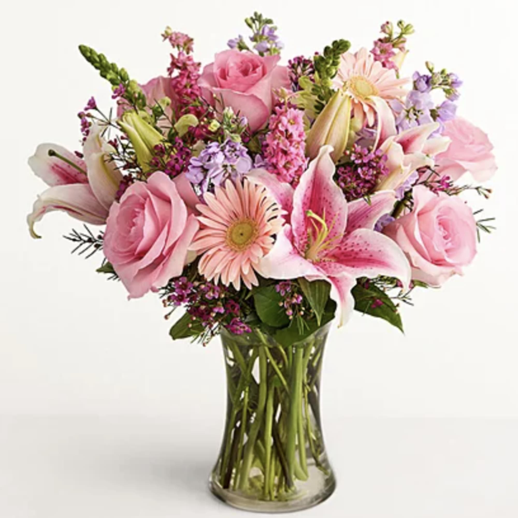 Pink roses and lilies arranged in a clear glass vase