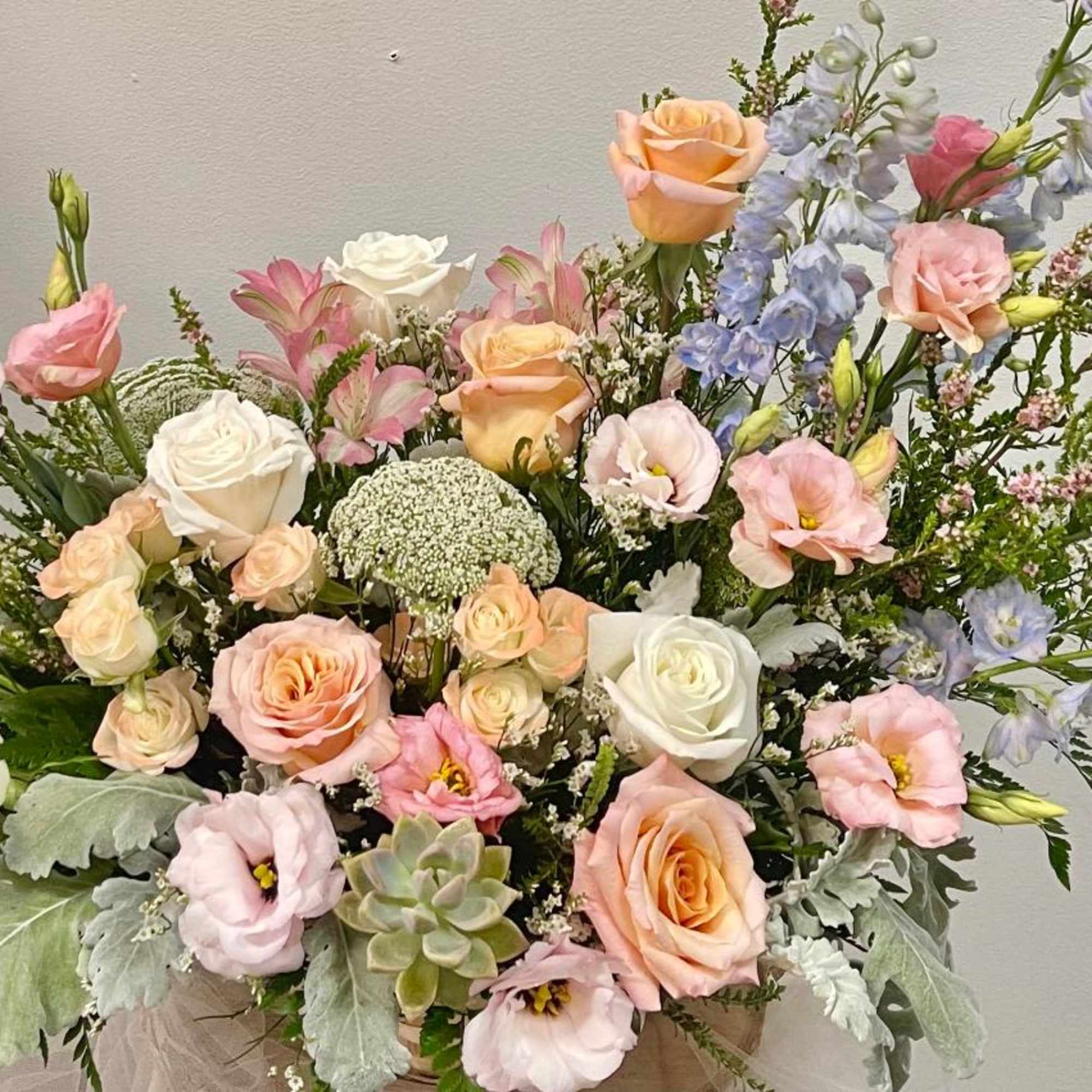 Pastel bouquet of roses, lisianthus, and blue delphinium in a vase