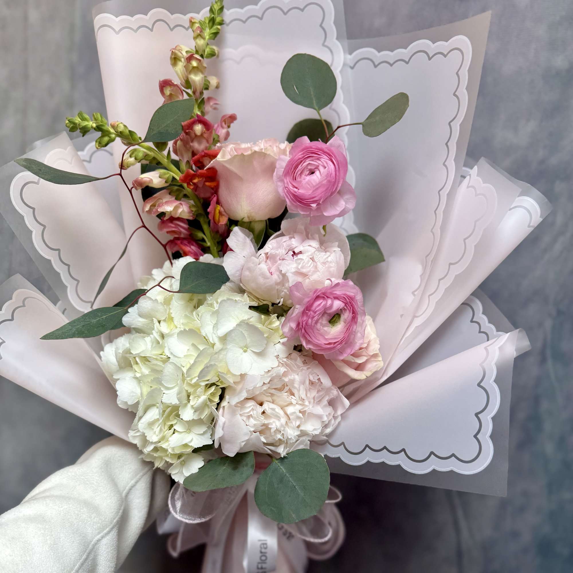 A romantic hand- tied bouquet of elegant soft blooms, hydrangeas, snapdragon and