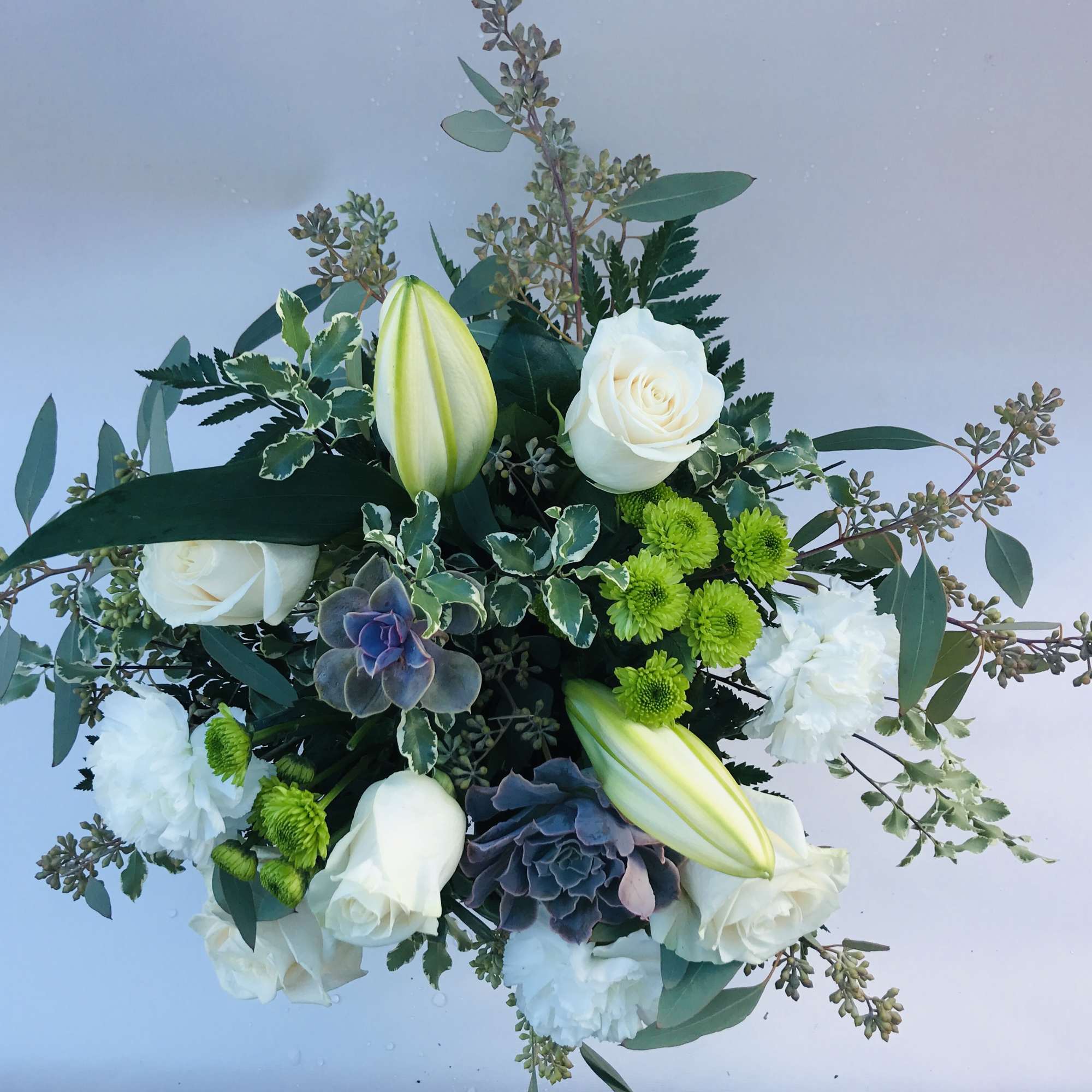 Bouquet of white roses, lilies, and green button mums with mixed foliage