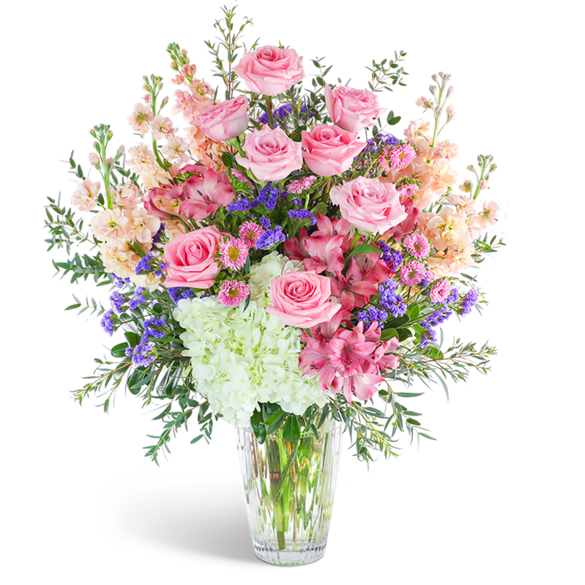 Pink roses and mixed blooms arranged in a clear glass vase