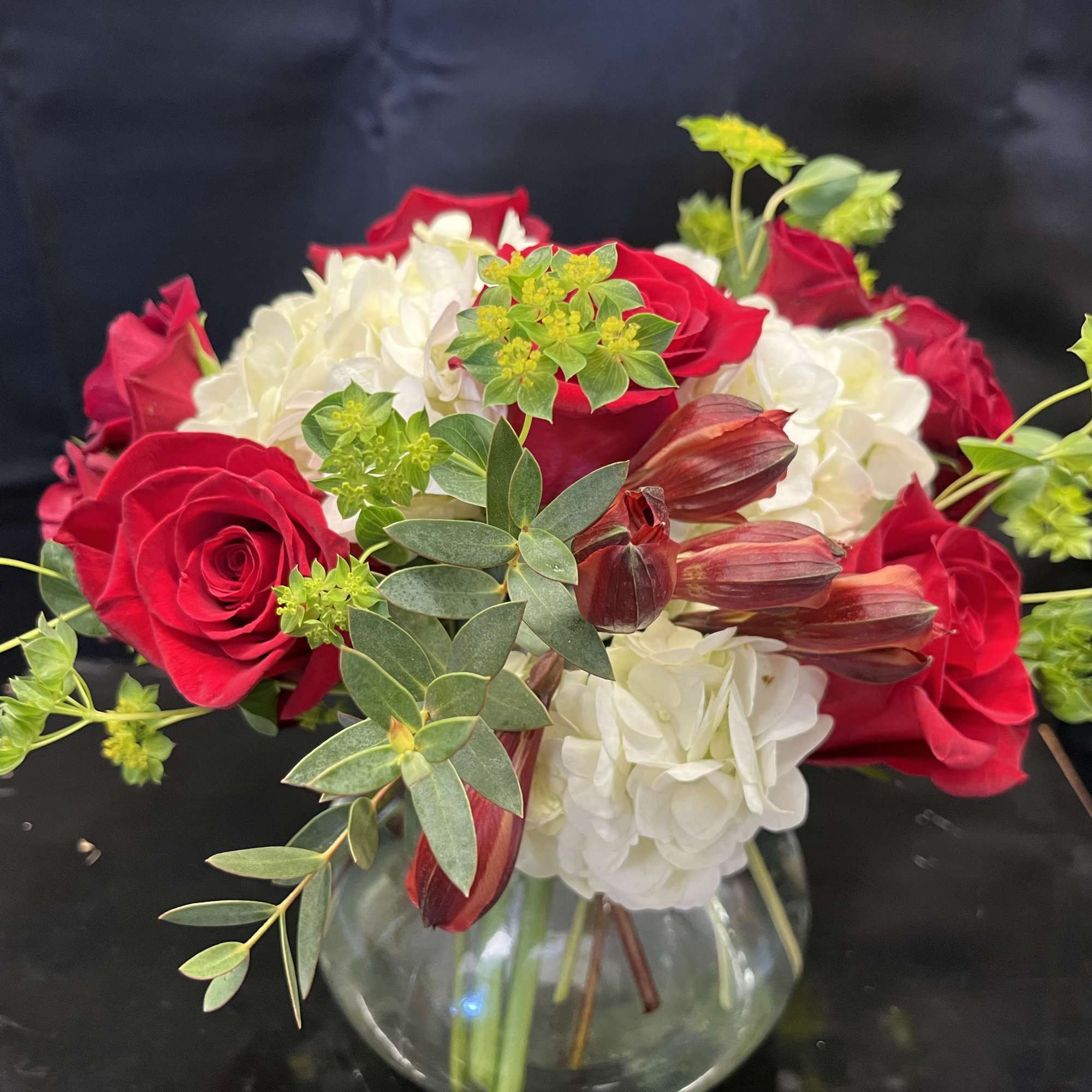 Red roses and white hydrangeas in a clear glass vase