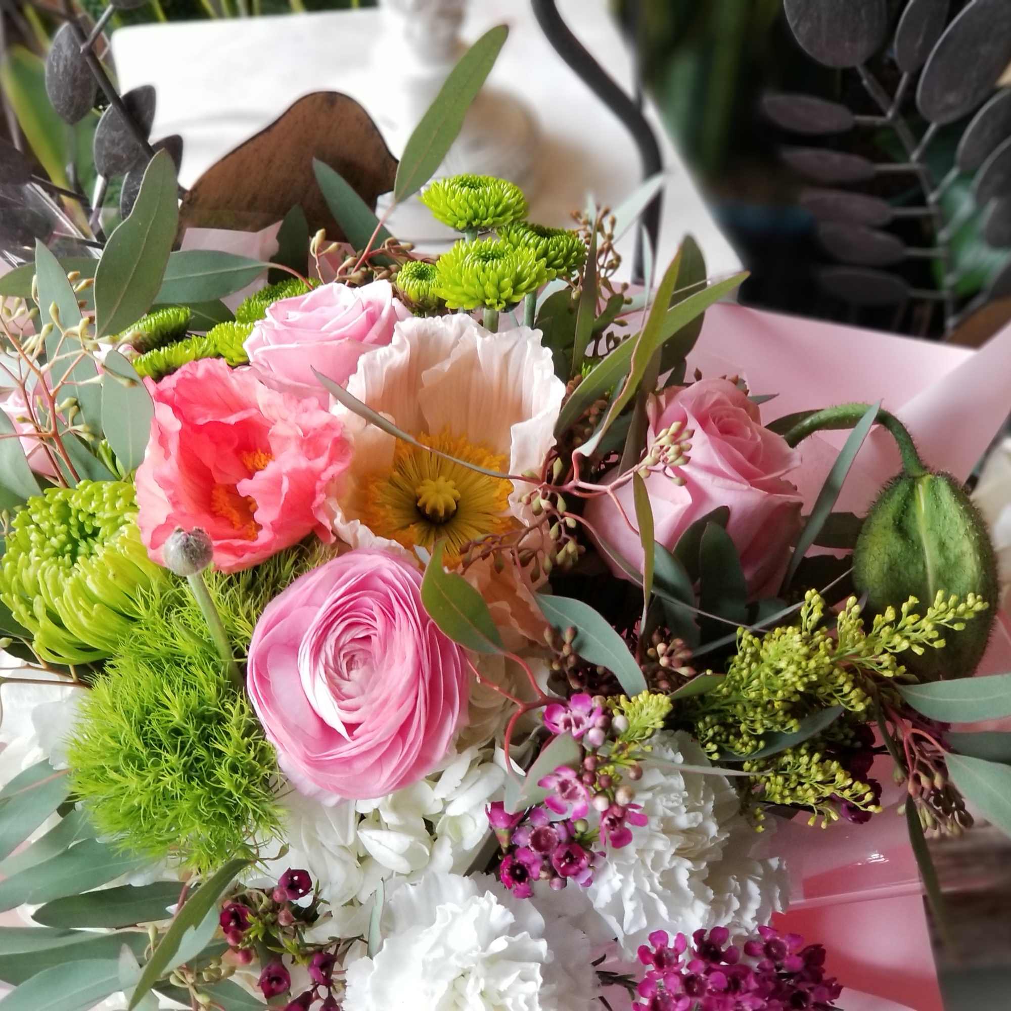 Bouquet of pink and white flowers with green accents wrapped in pink paper