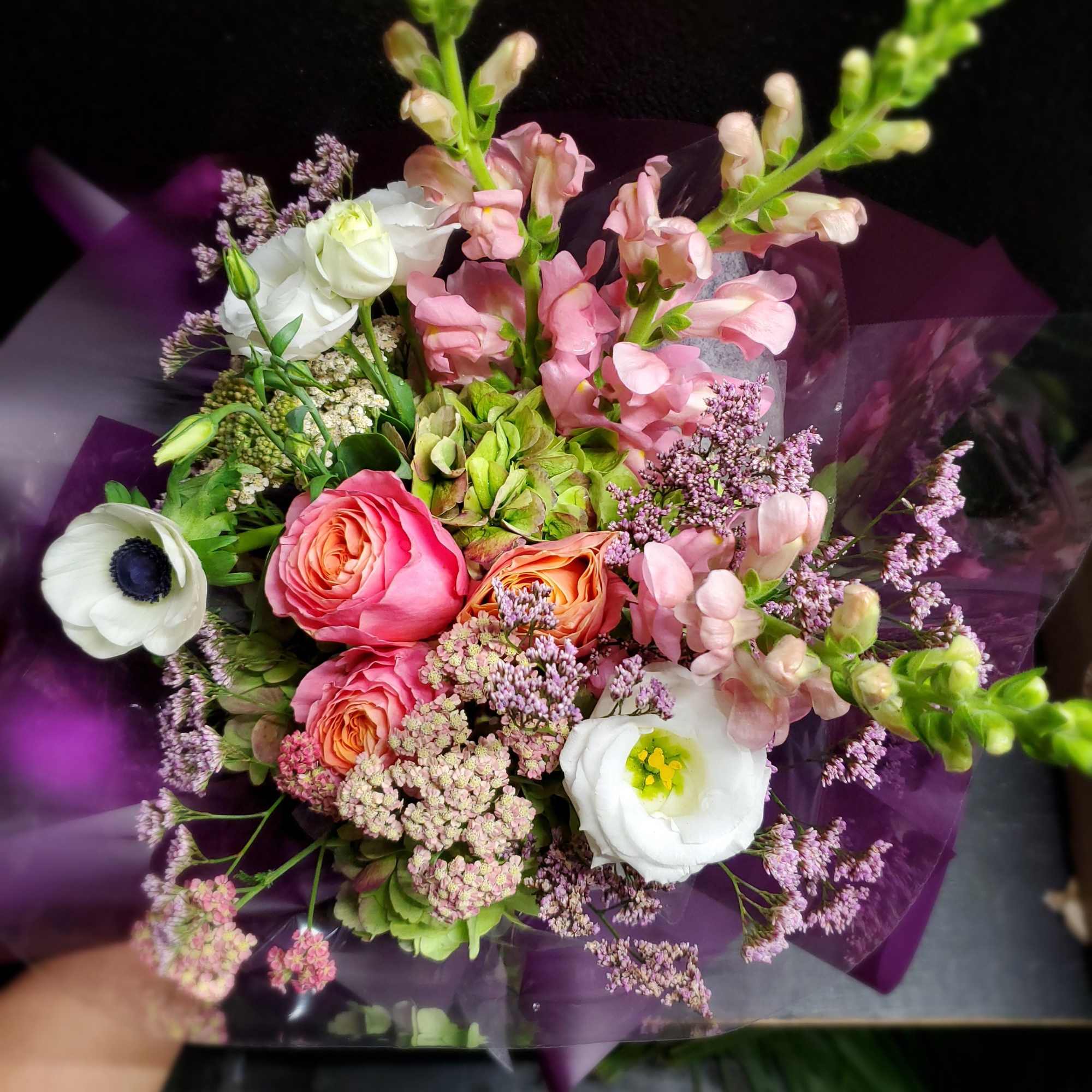 Bouquet of pink and white flowers wrapped in purple paper