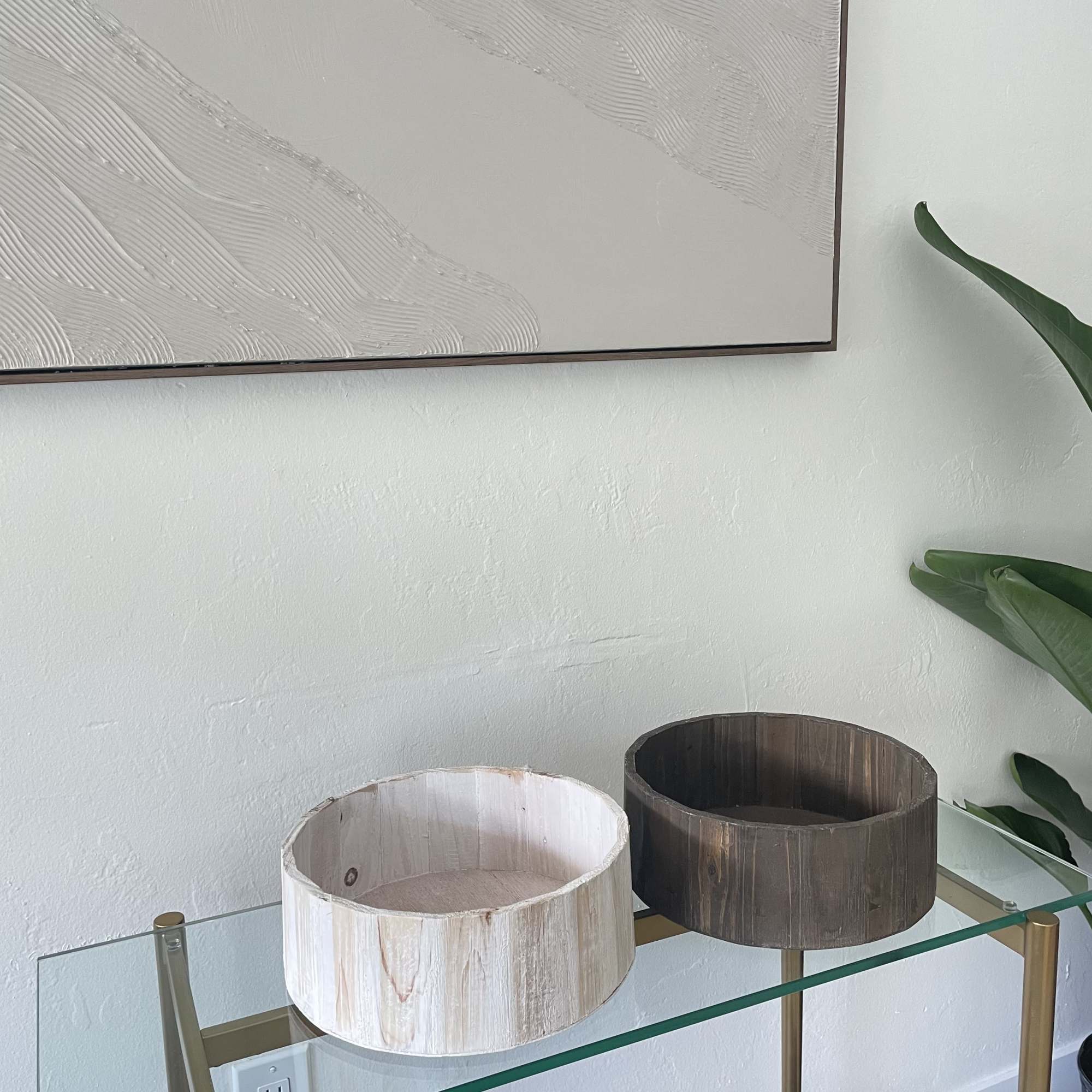 Two empty round wooden containers sit on a glass shelf.