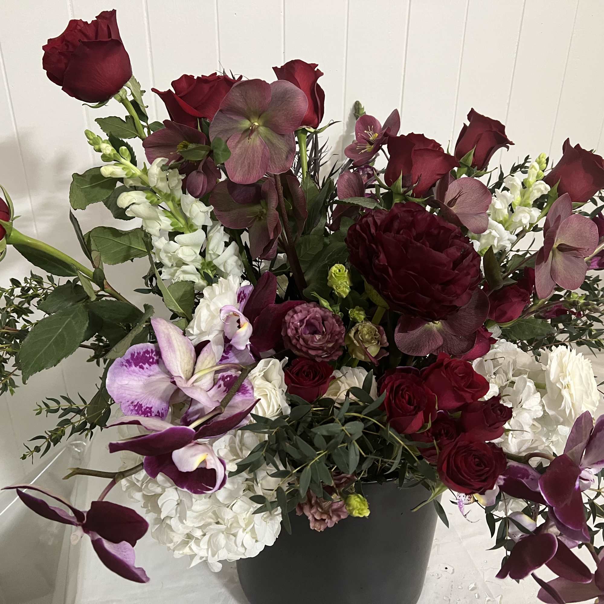 Deep red roses and purple orchids in a black vase