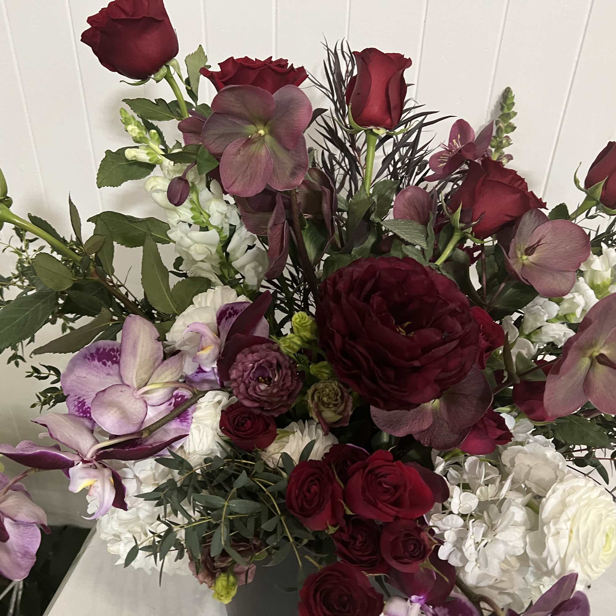 A designer's choice arrangement focusing on red roses accented with seasonal high-end