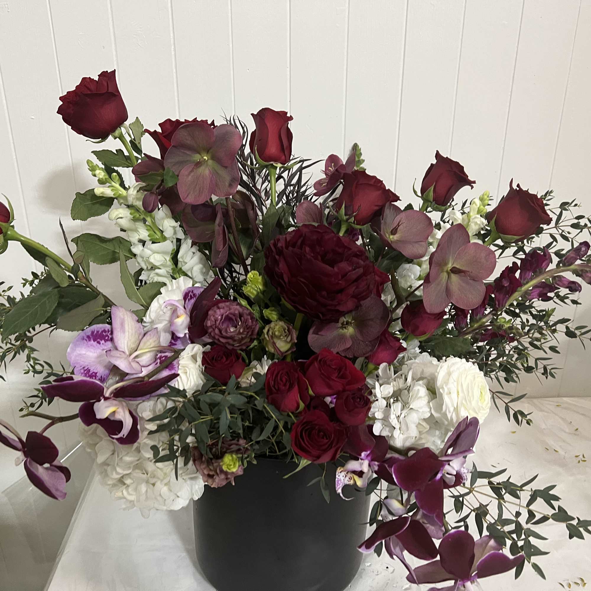 Deep red roses and purple orchids in a black vase