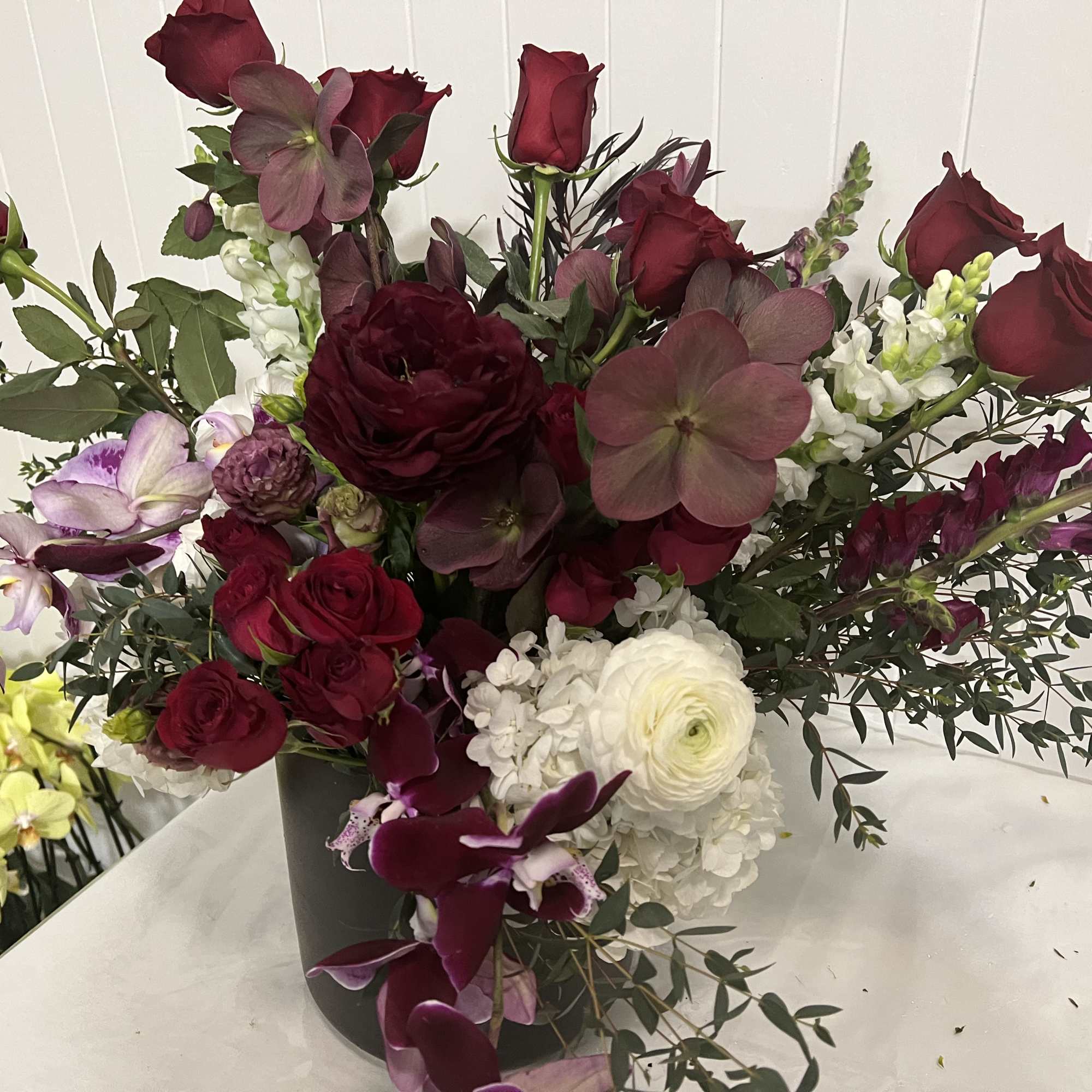 Deep red roses and mixed blooms arranged in a black vase
