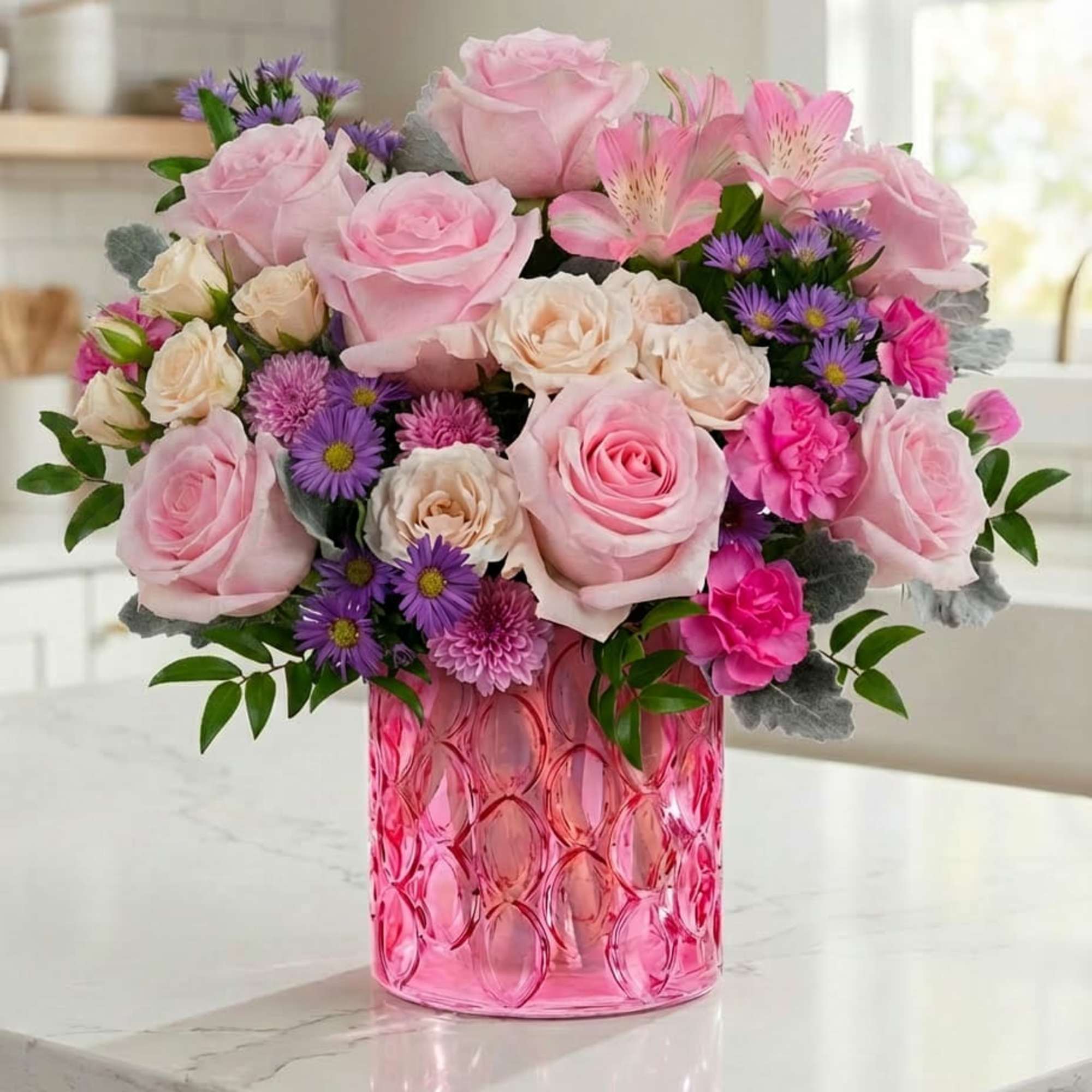 Pink roses and purple daisies in a pink glass vase