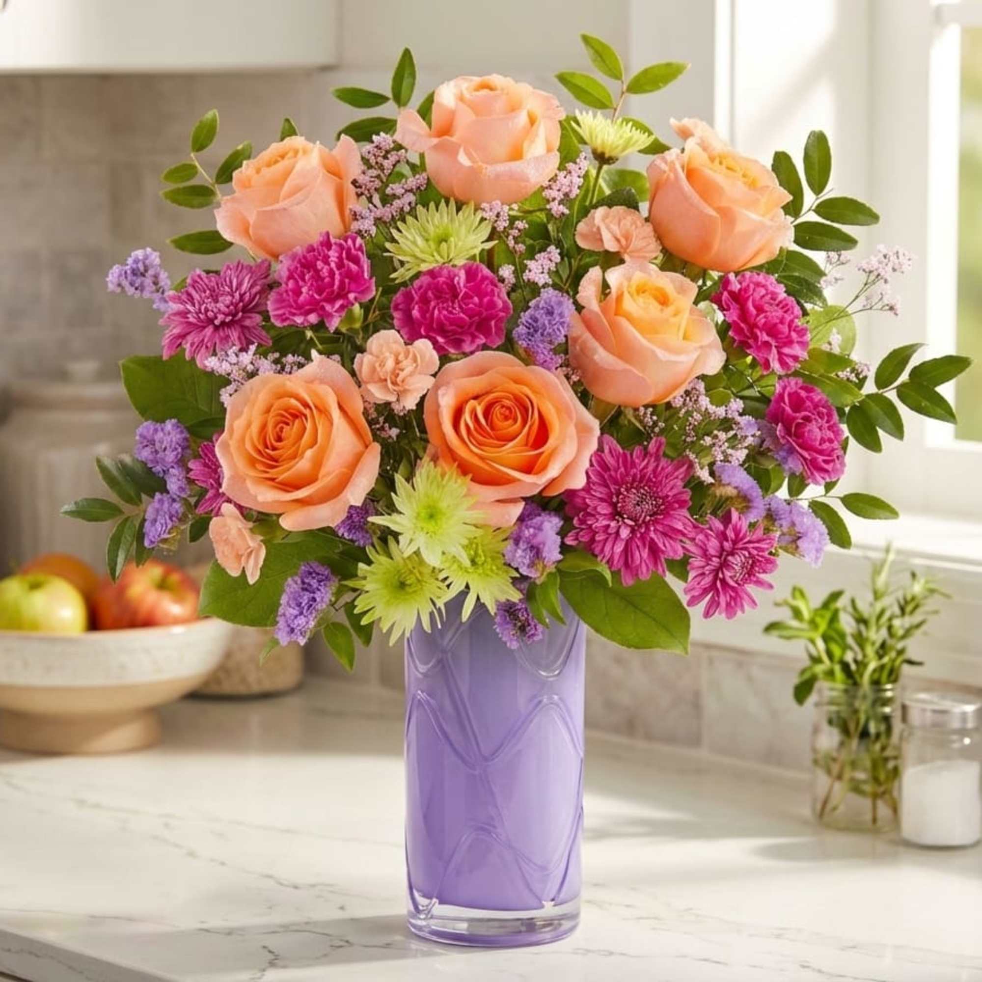 Peach and pink flower arrangement in a purple glass vase