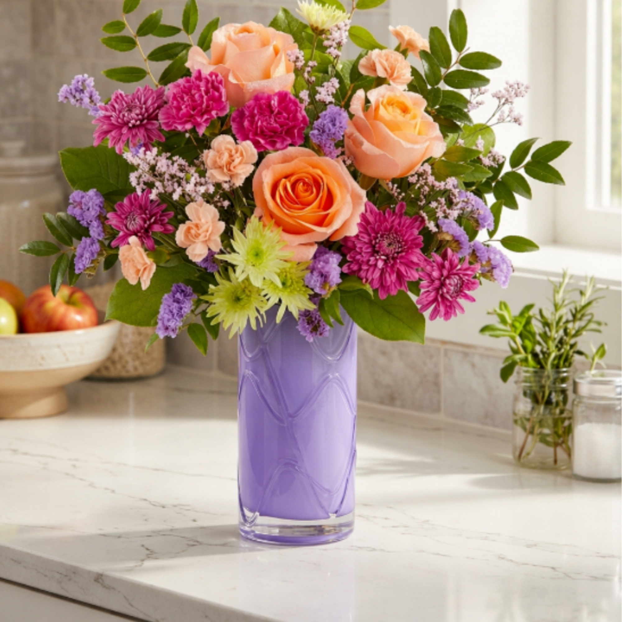 Mixed bouquet of peach roses, pink blooms, and purple flowers in a lavender vase