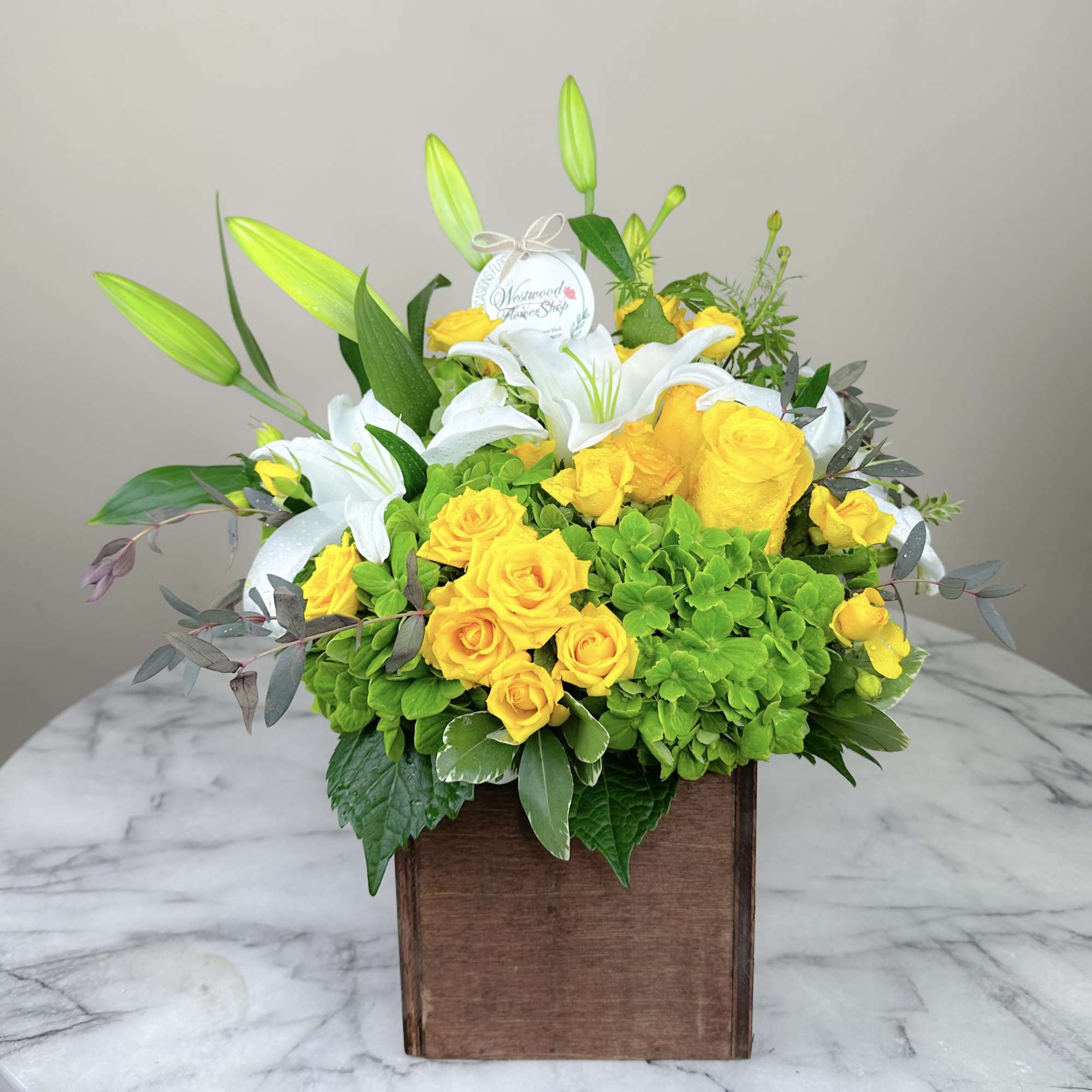 Yellow roses and white lilies in a wooden box arrangement
