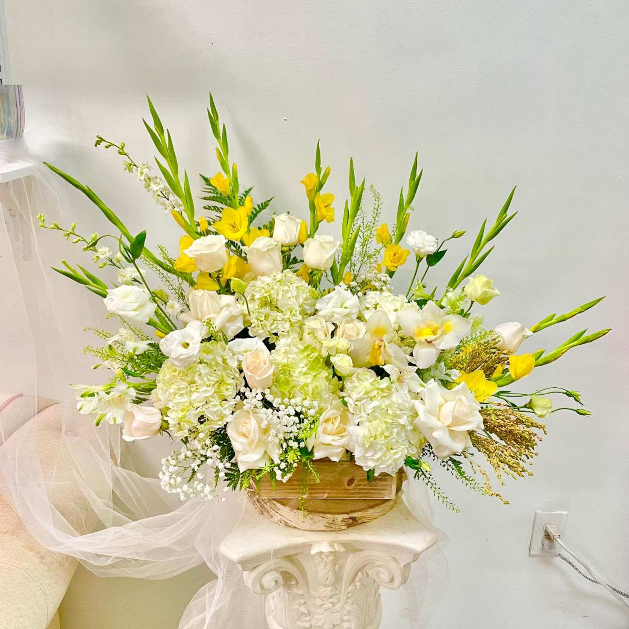 Large white and yellow floral arrangement in a wooden container