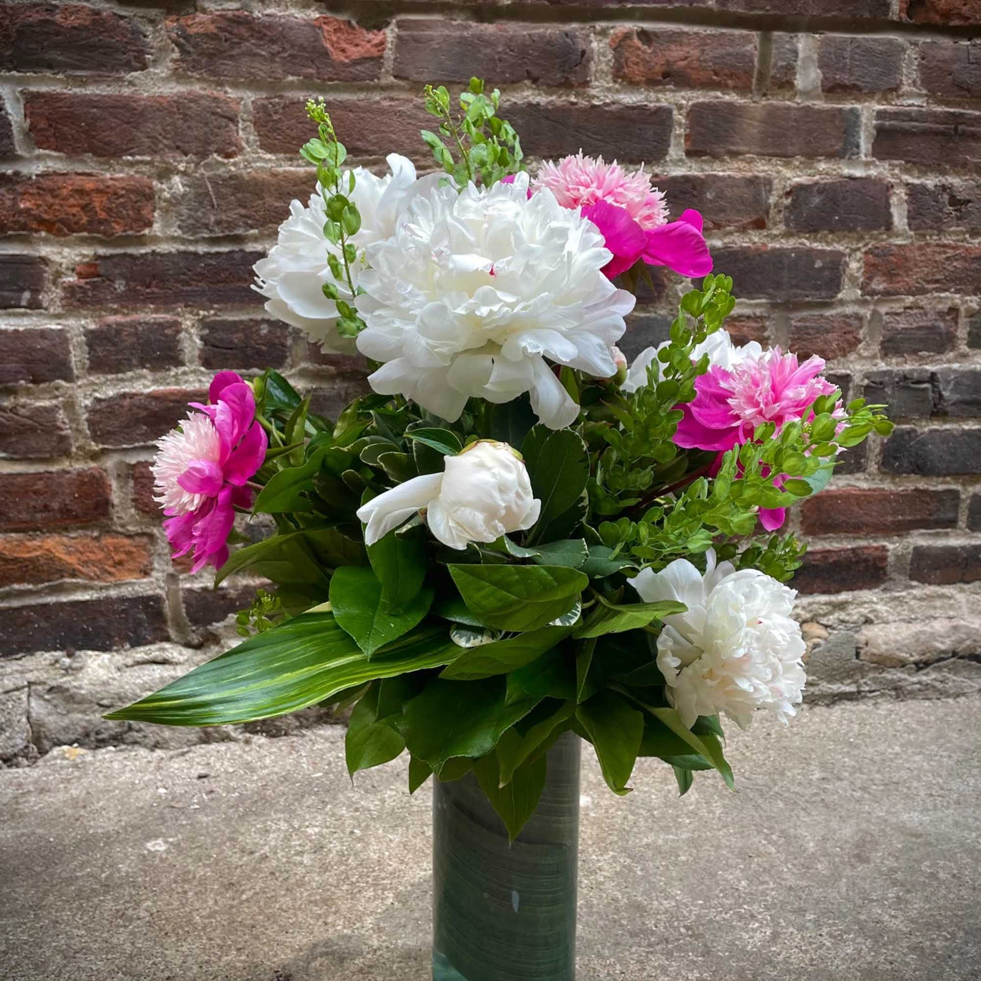 White and pink floral arrangement in a tall green vase