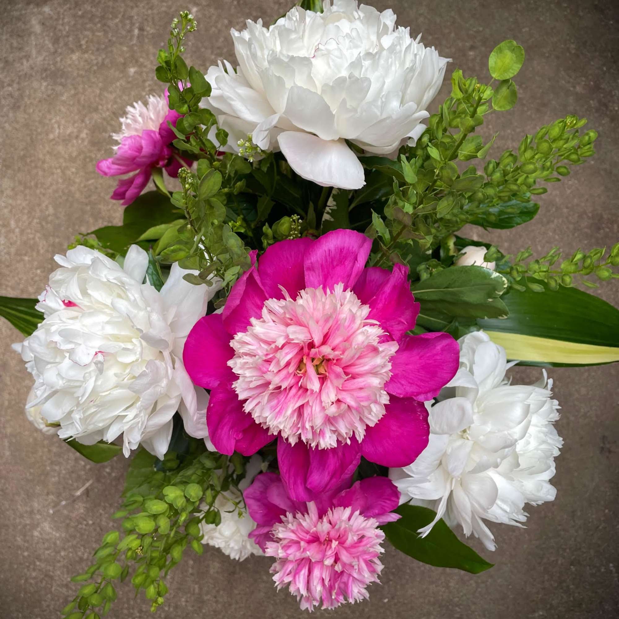 Pink and white peonies with green filler in a bouquet