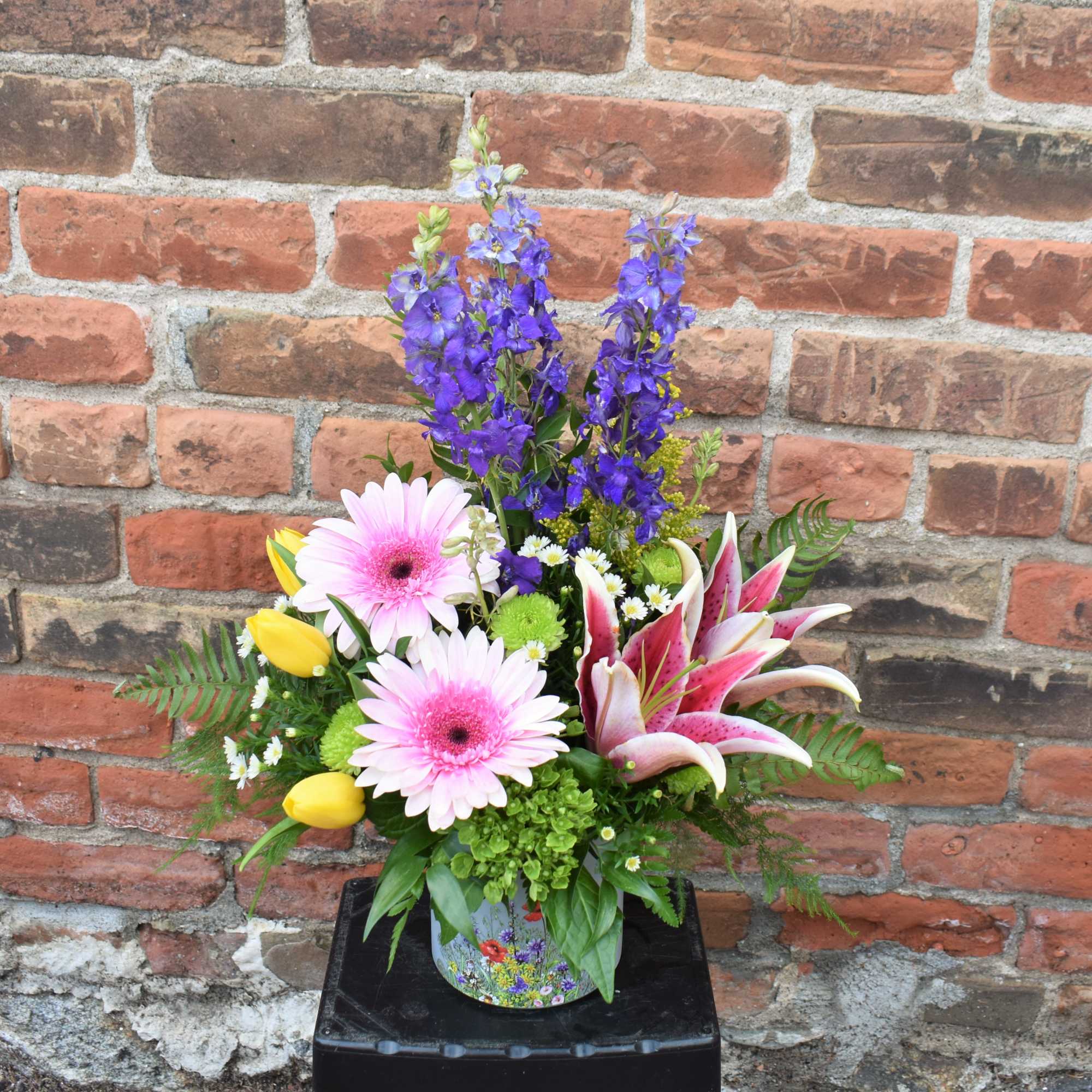 Bright summery flowers of lilies, tulips, larkspur, hydrangea, Gerber daisies, and mums