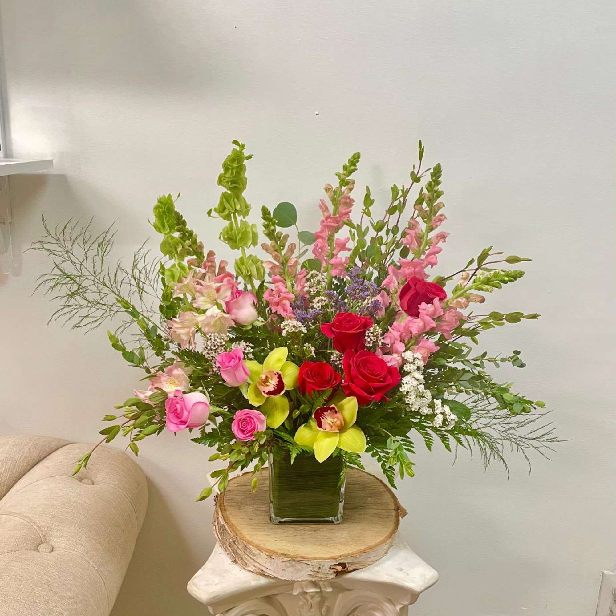 Mixed bouquet of roses, orchids, and snapdragons in a glass vase
