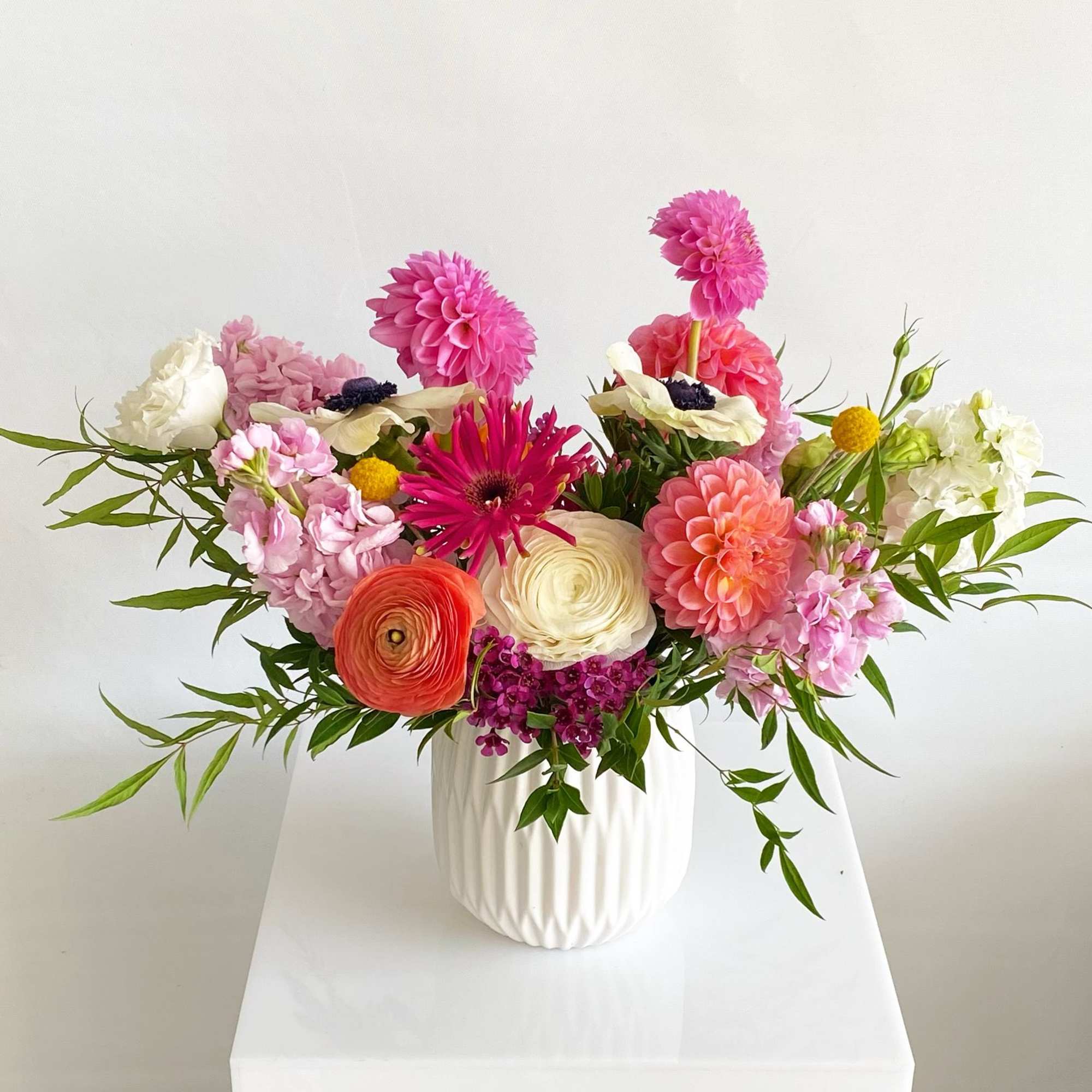Colorful mixed bouquet in a white vase with pink, coral, and white blooms