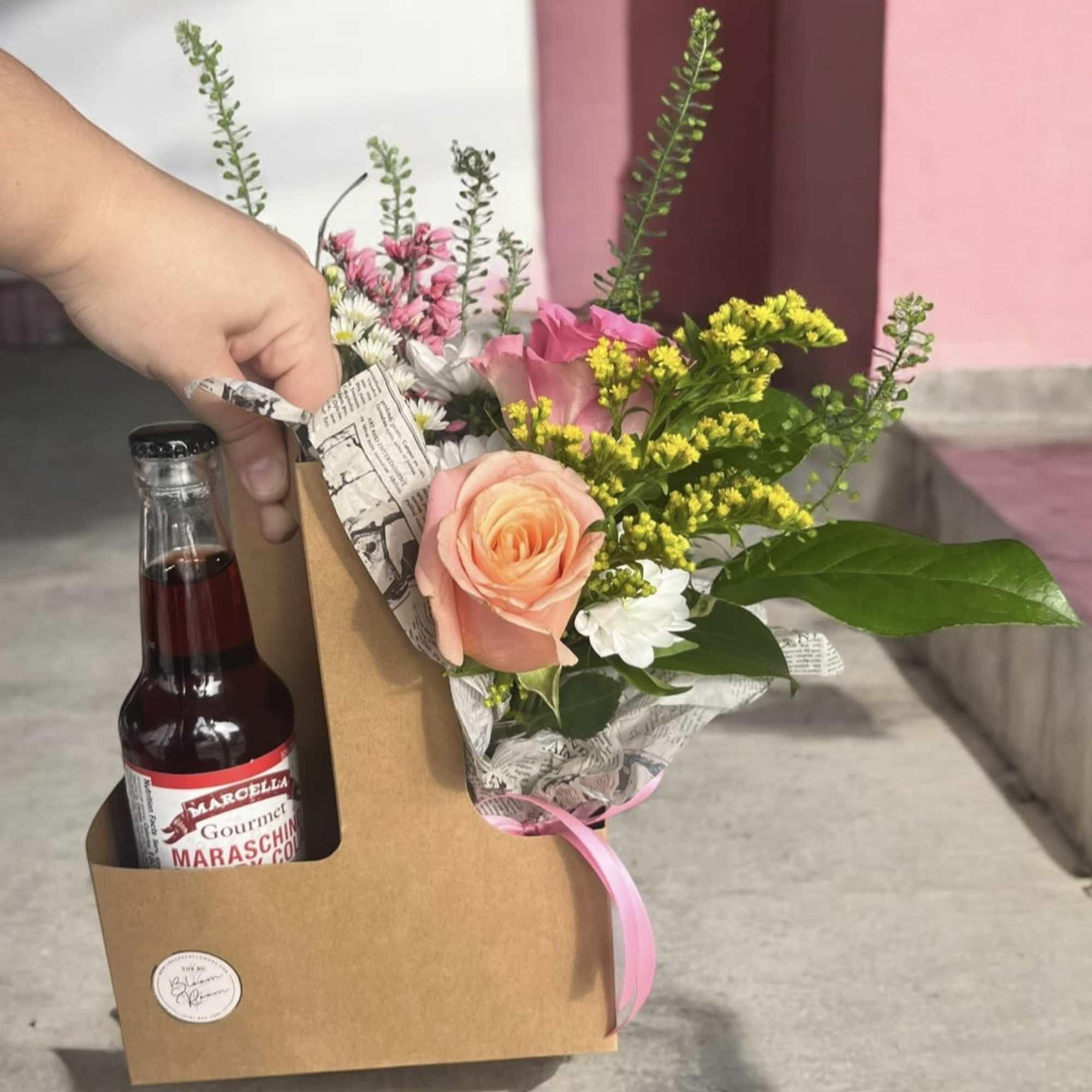 Bouquet with pink and peach roses in a kraft gift box beside a maraschino cherry bottle