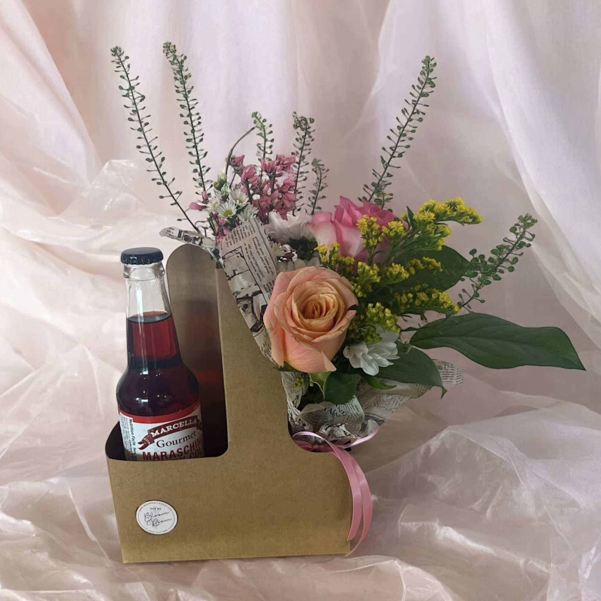 Flower arrangement in a cardboard carrier with a maraschino cherry bottle