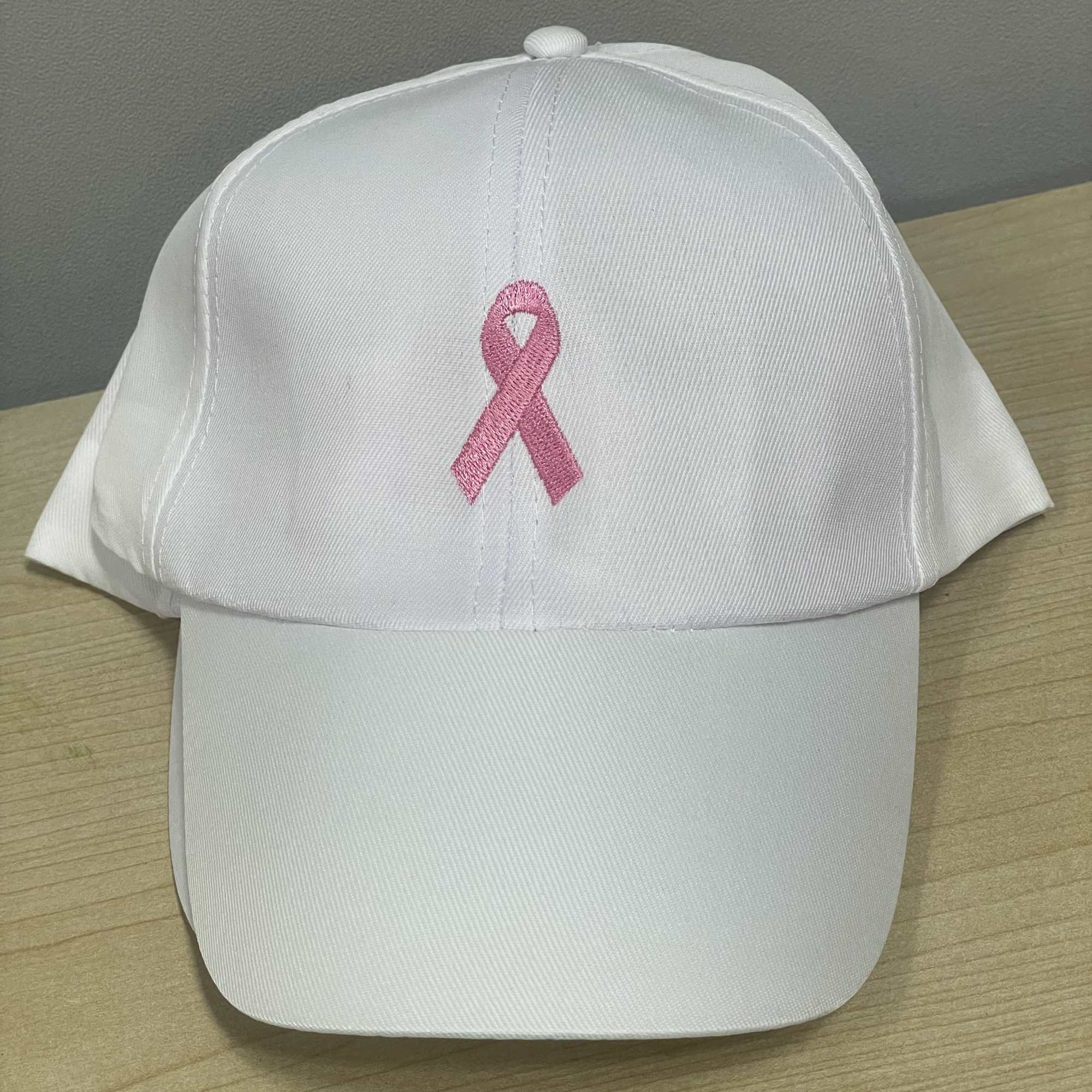 White baseball cap with a pink ribbon embroidered on the front