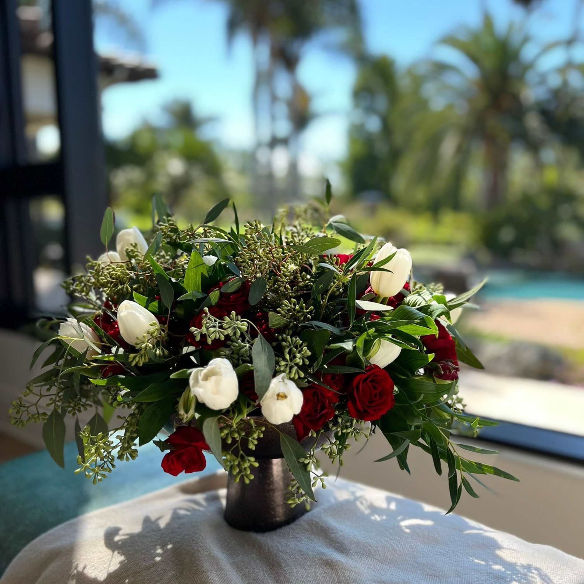 Red and white rose arrangement in a dark vase