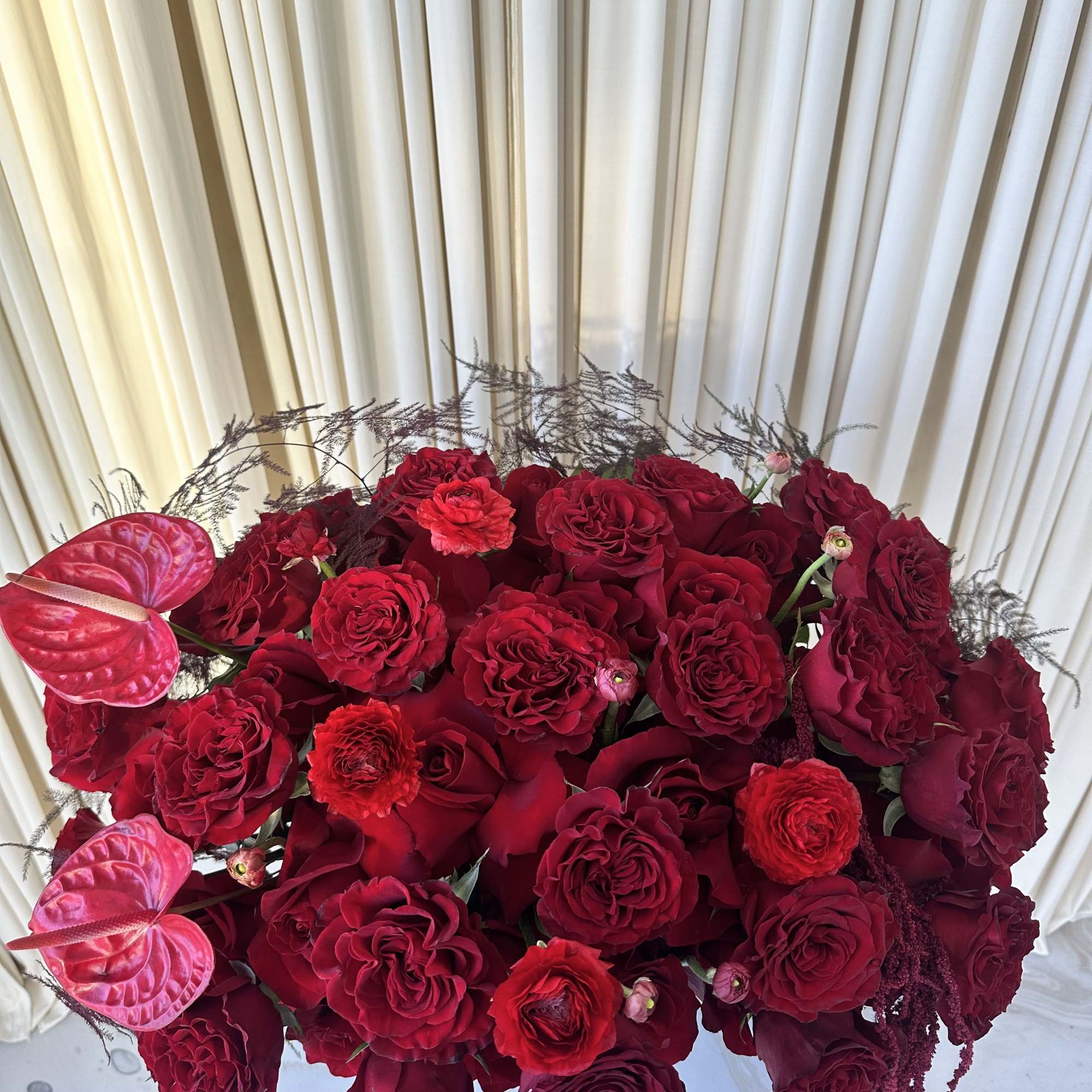 A lush mound of deep red roses and ranunculus creates the first