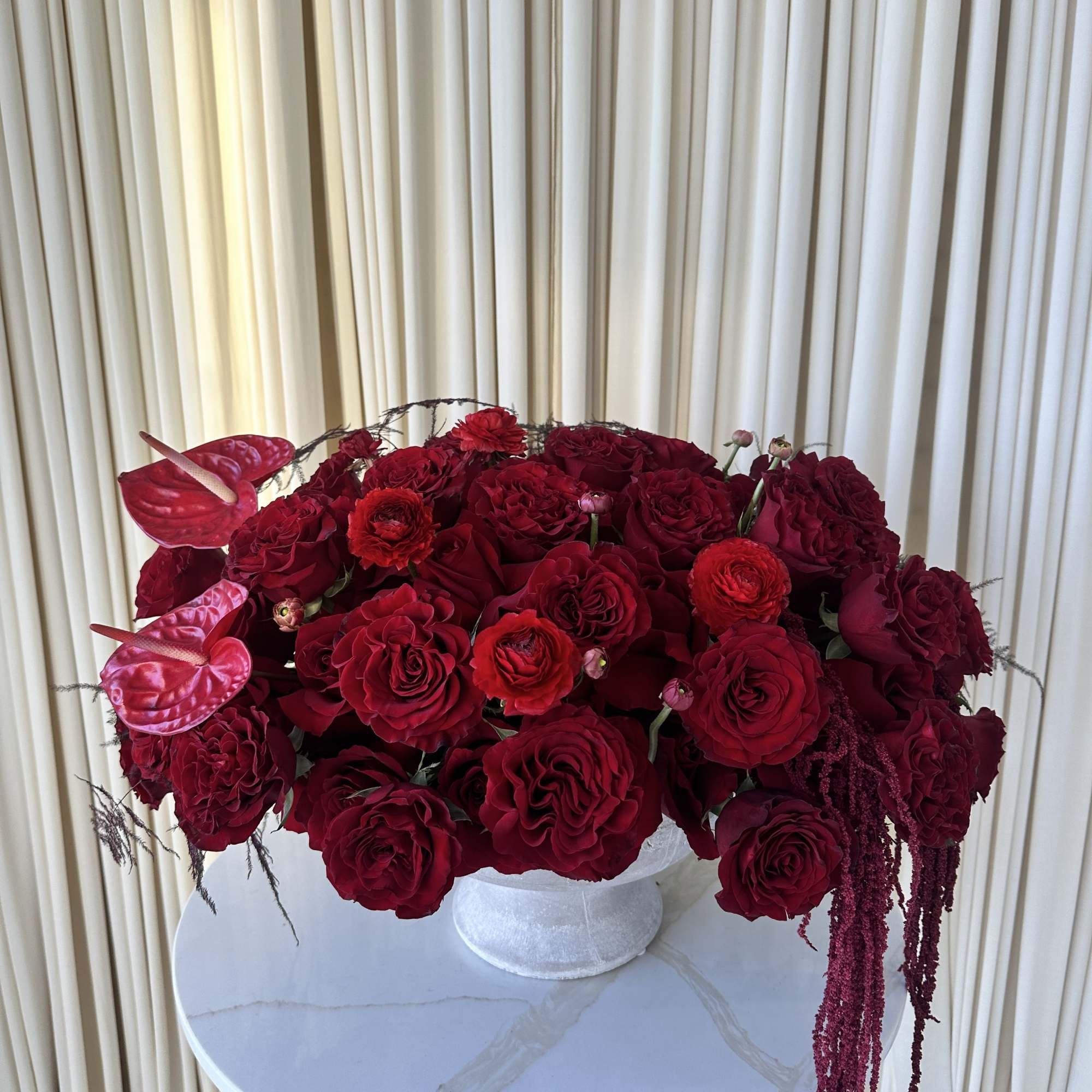 A lush mound of deep red roses and ranunculus creates the first