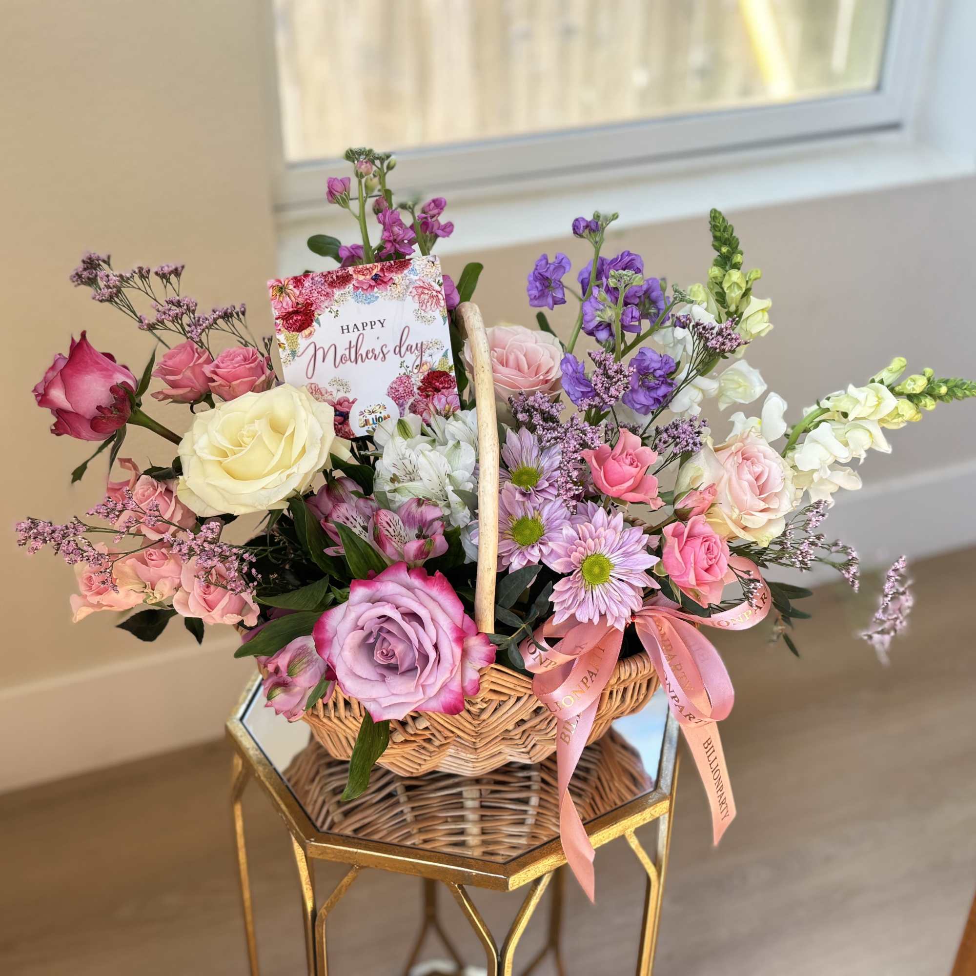 Basket of mixed pink, purple, and white flowers with a Mother's Day card
