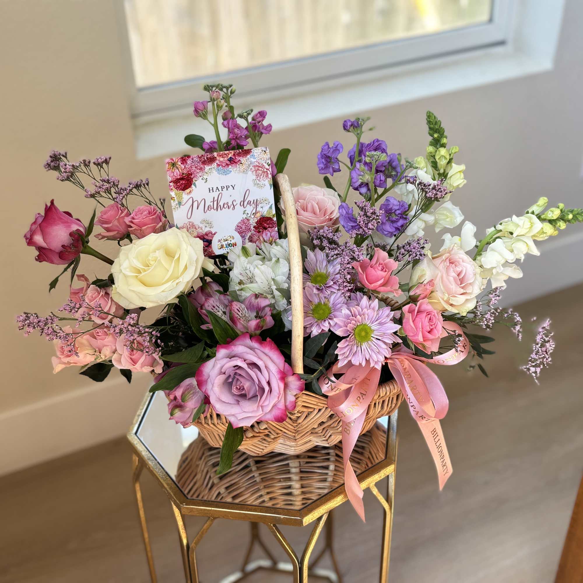 Basket arrangement of roses, daisies, and snapdragons with a Mother's Day card