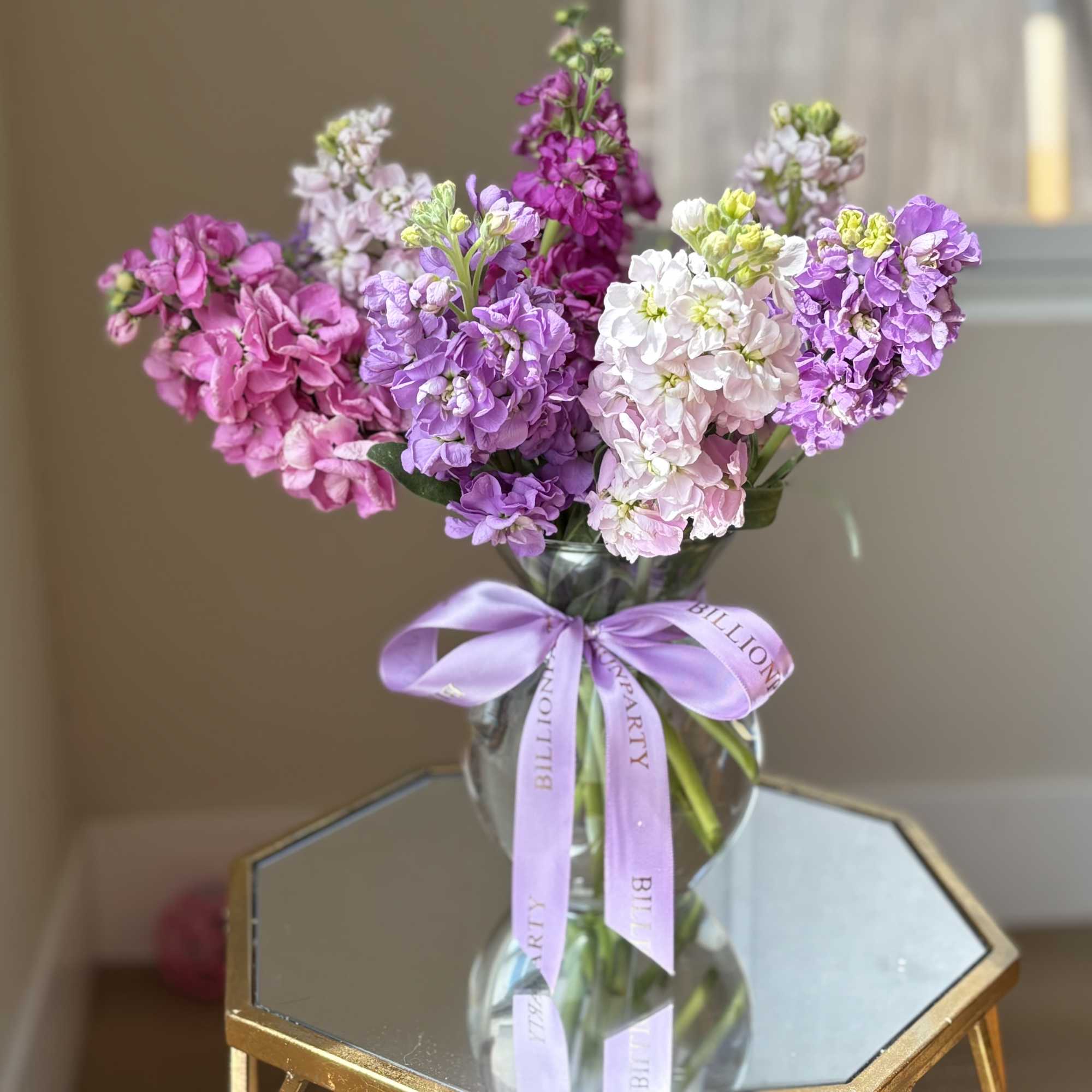 Bouquet of pink and purple flowers in a glass vase with a lavender ribbon