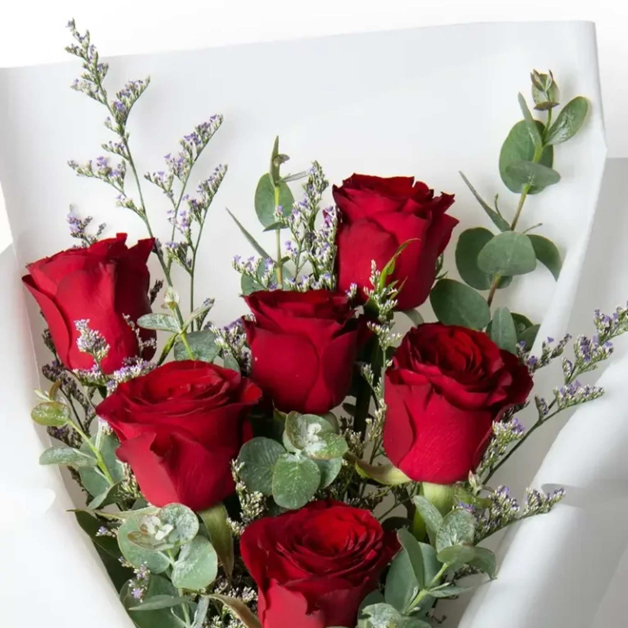 Bouquet of red roses with eucalyptus and purple filler flowers