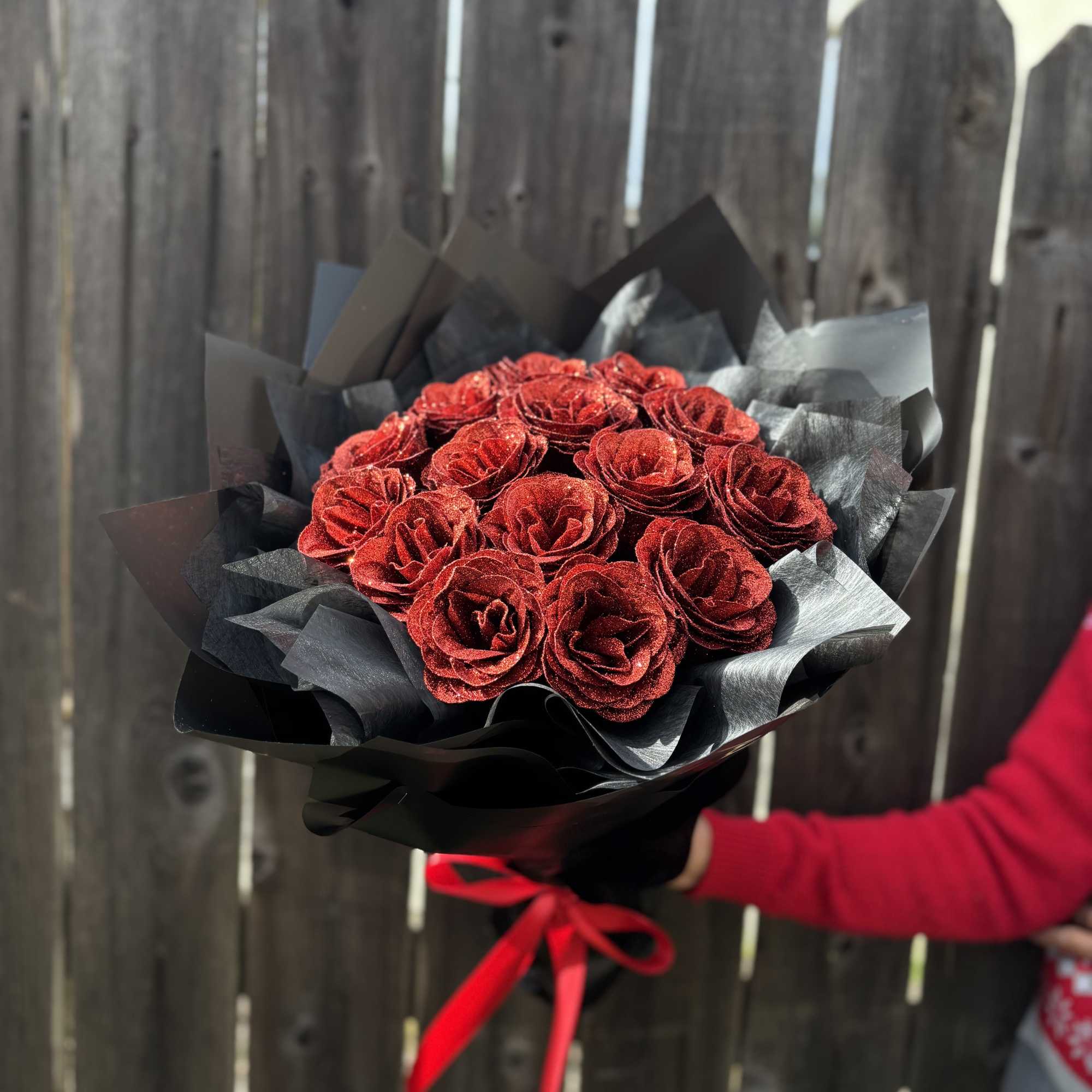 Bouquet of red roses wrapped in black paper with a red ribbon