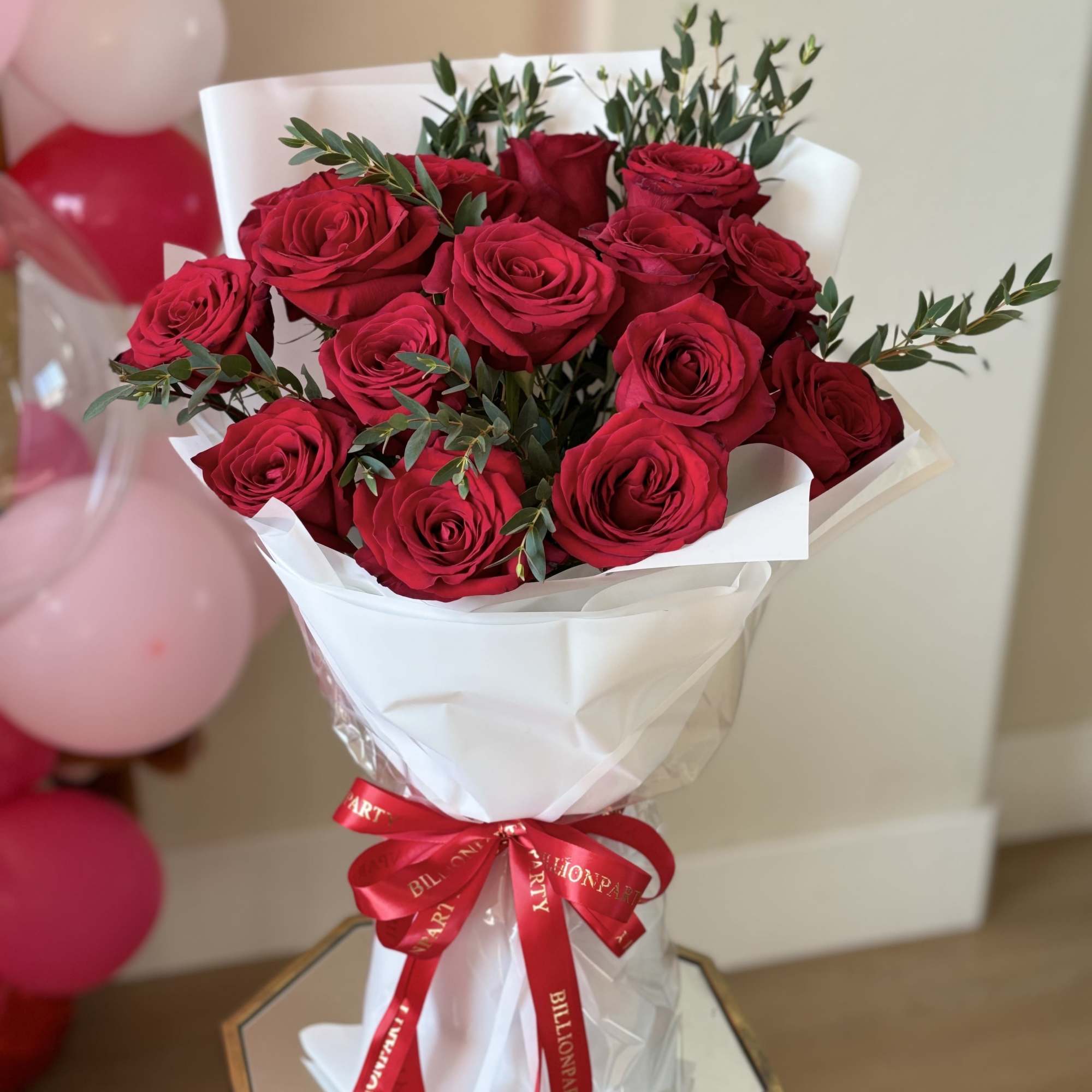 Bouquet of red roses wrapped in white paper with a red ribbon