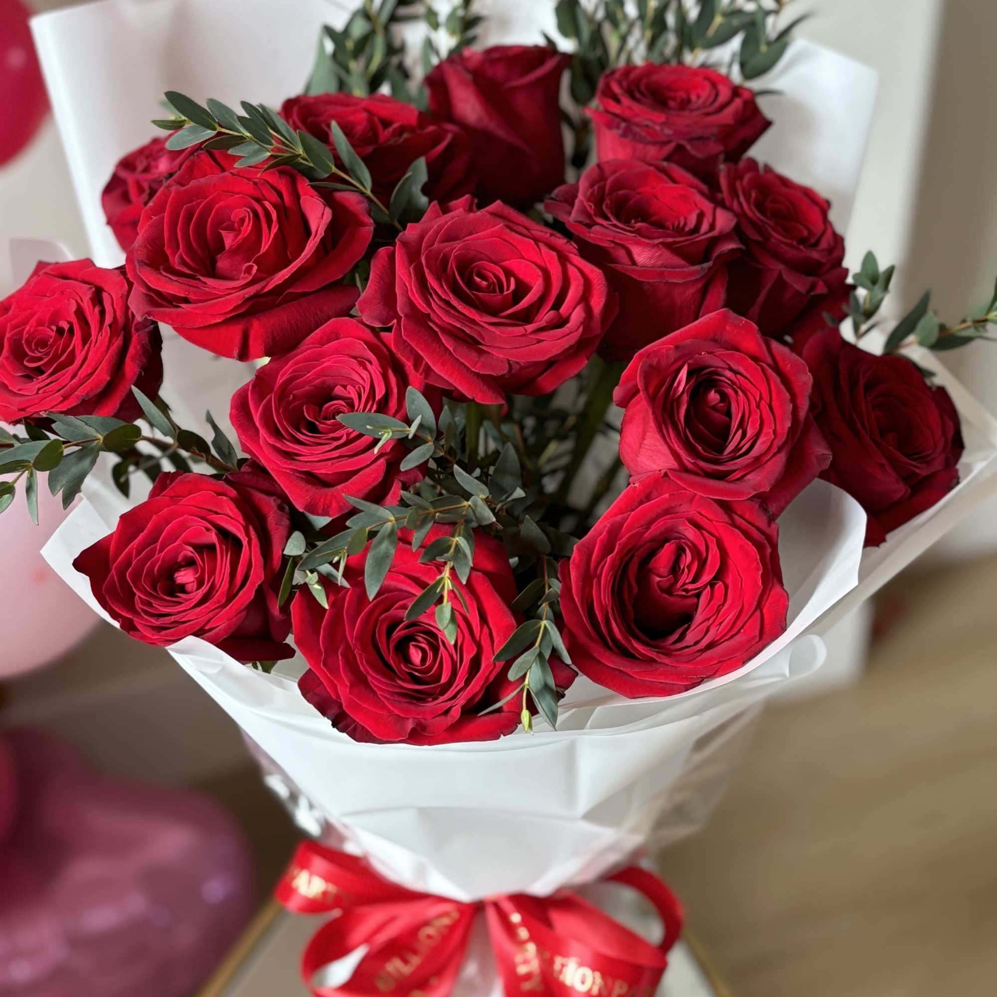 Bouquet of red roses wrapped in white paper with a red ribbon