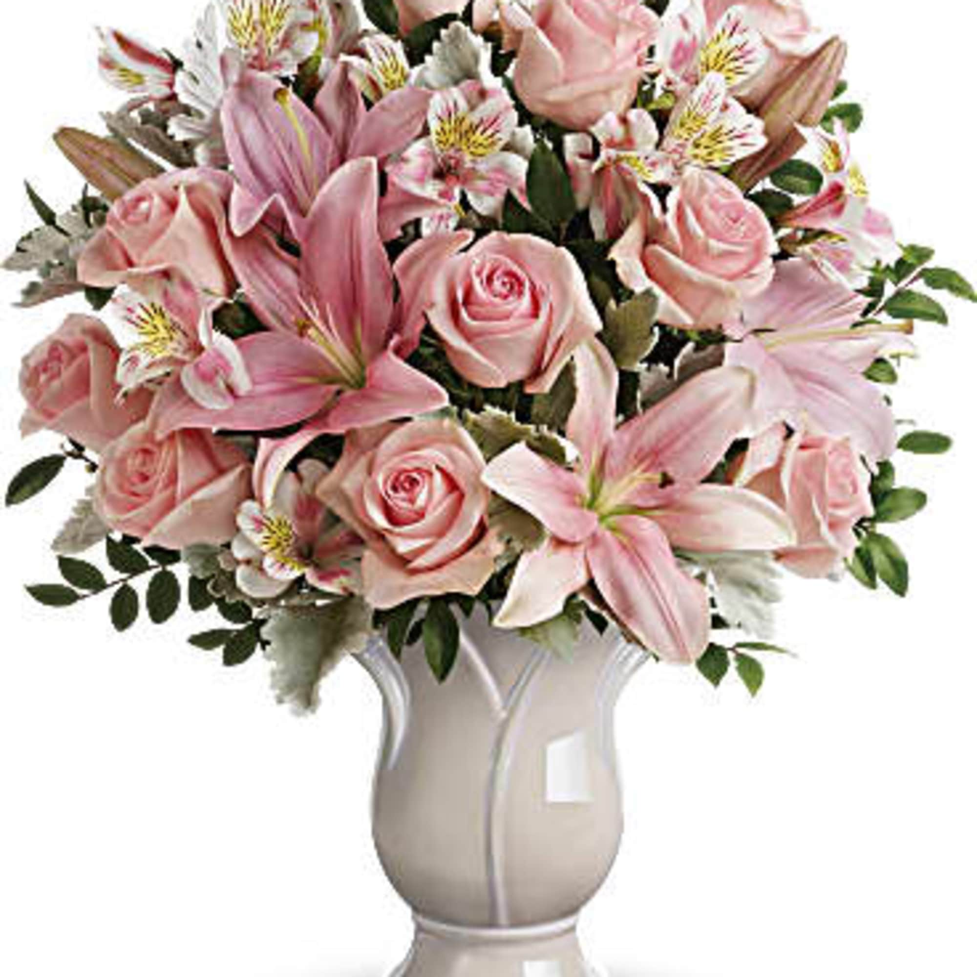 Pink roses, lilies, and white alstroemeria arranged in a pale ceramic vase