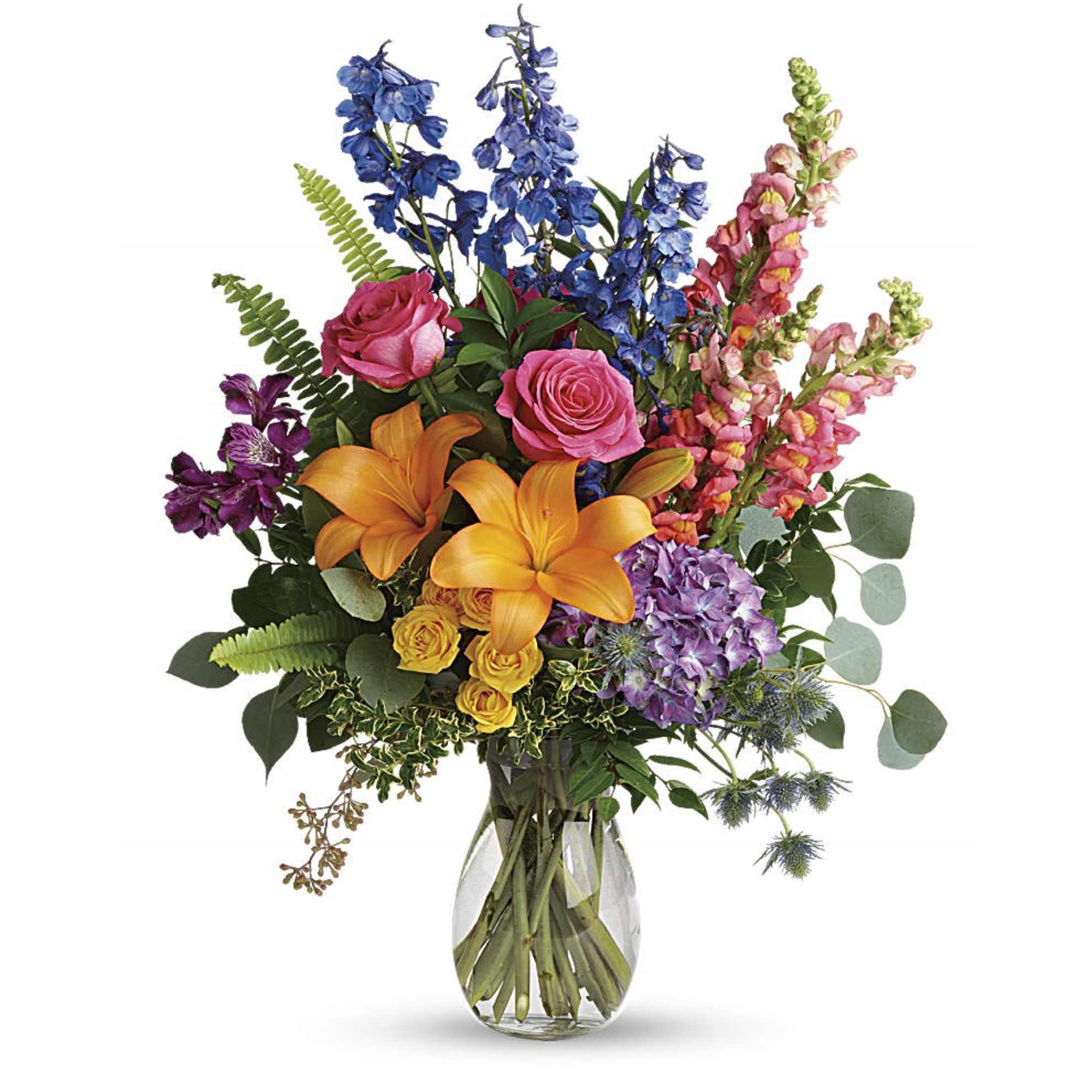 Tall mixed bouquet of orange lilies, pink roses, and assorted bright flowers in a clear glass vase