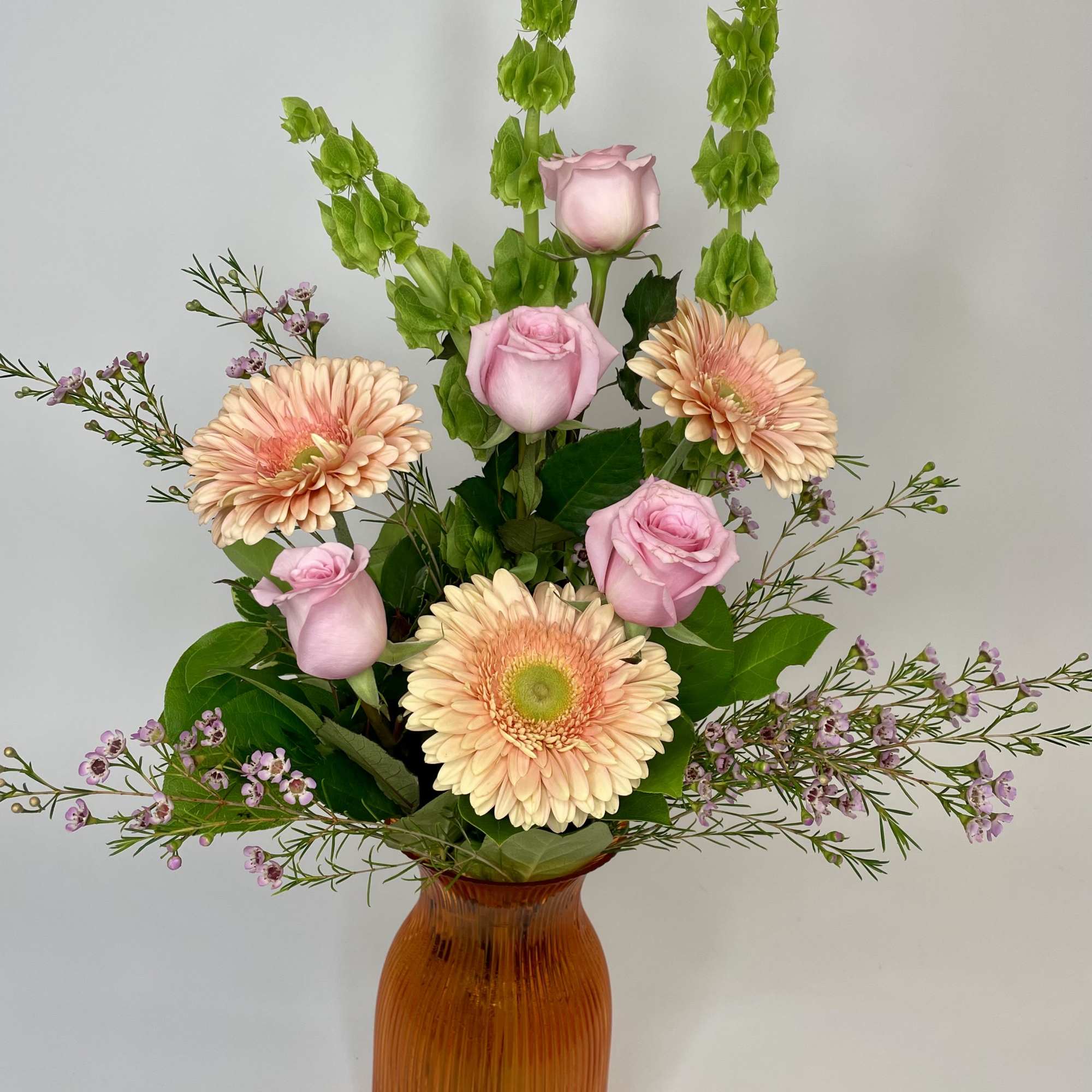 A beautiful mixture of Peach Gerbera Daisys accented with pink waxflower in
